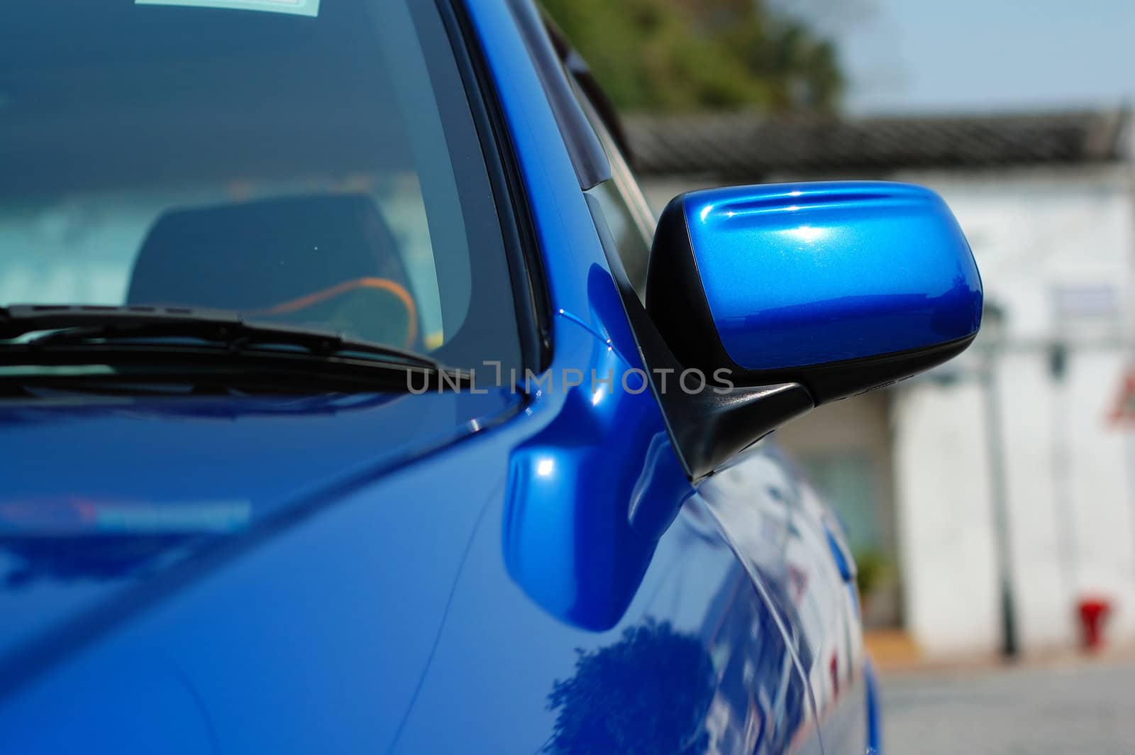 Close shot of right side mirror of shiny blue car