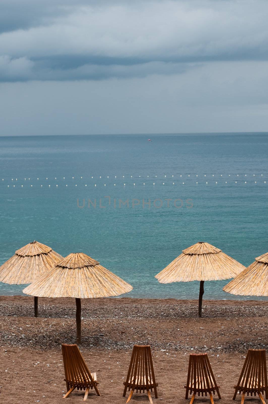 empty chairs and umbrellas waiting for the storm on the beach