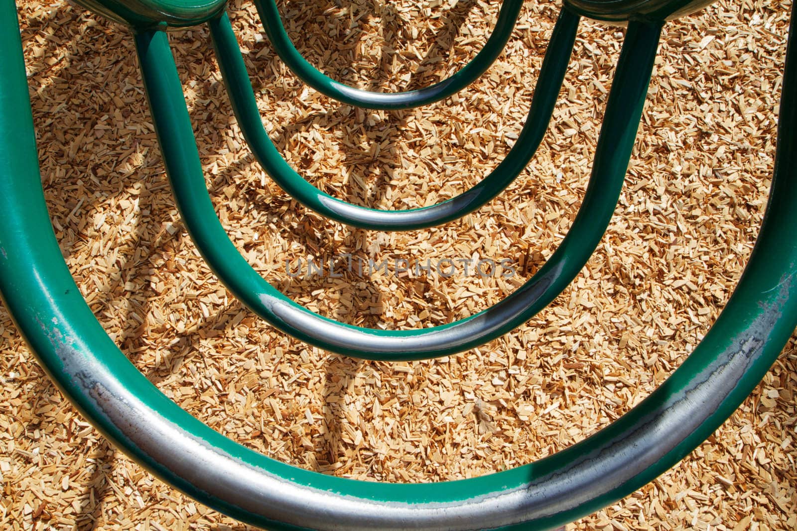 Green circular playground ladder with an abstract view looking down at wood chips