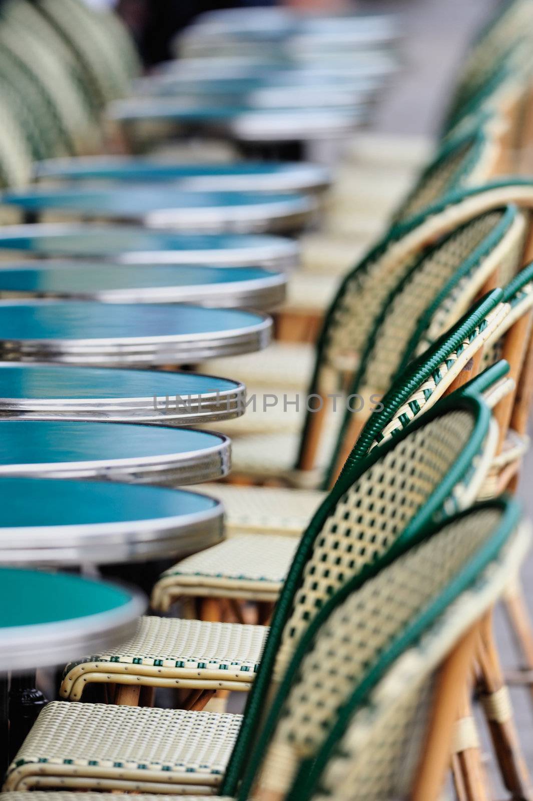 Several round tables and chairs in cafe in Paris. Photo with tilt-shift effect