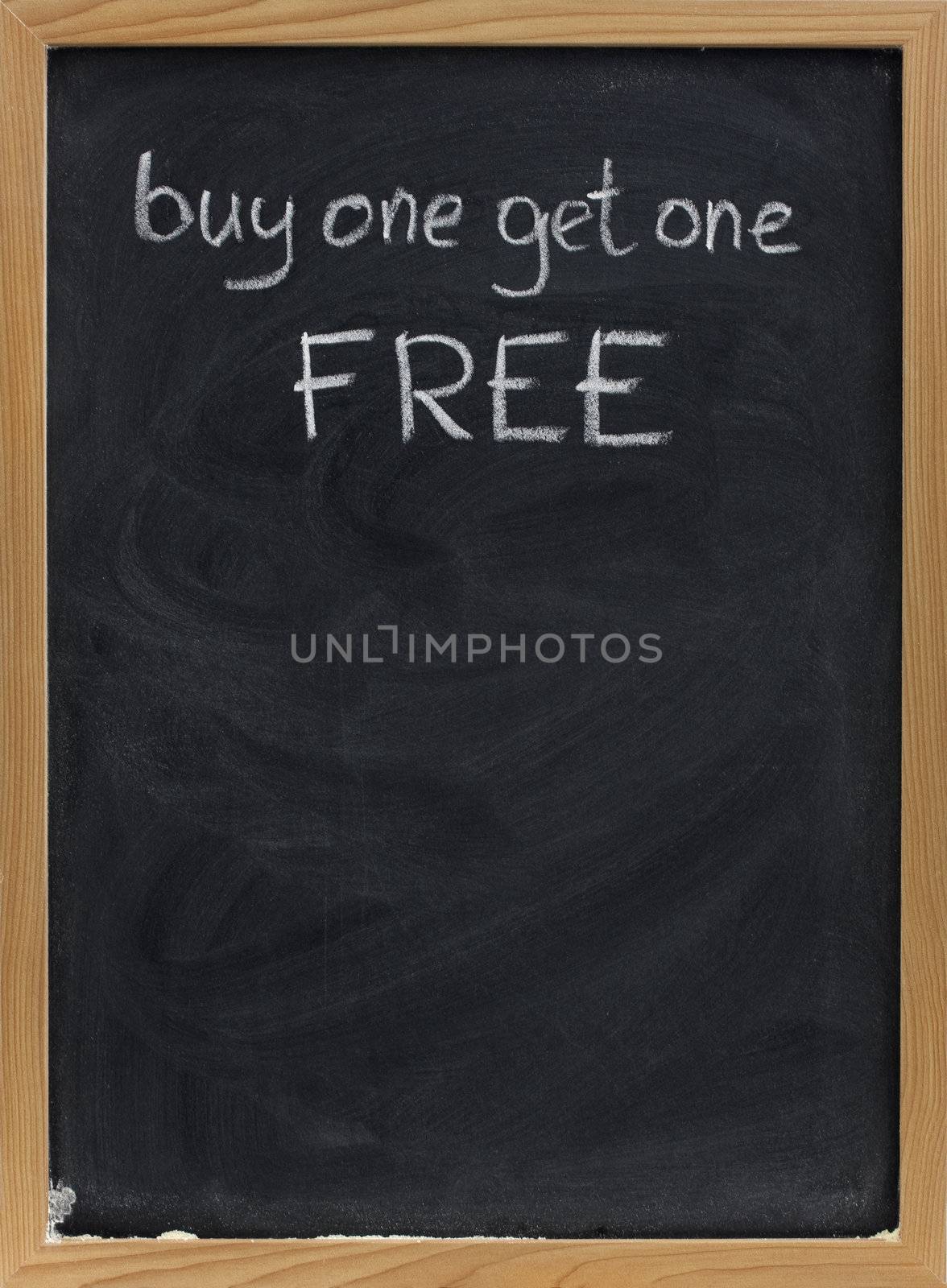 buy one get one free offer - discount sale advertisement handwritten with white chalk on blackboard, copy space below