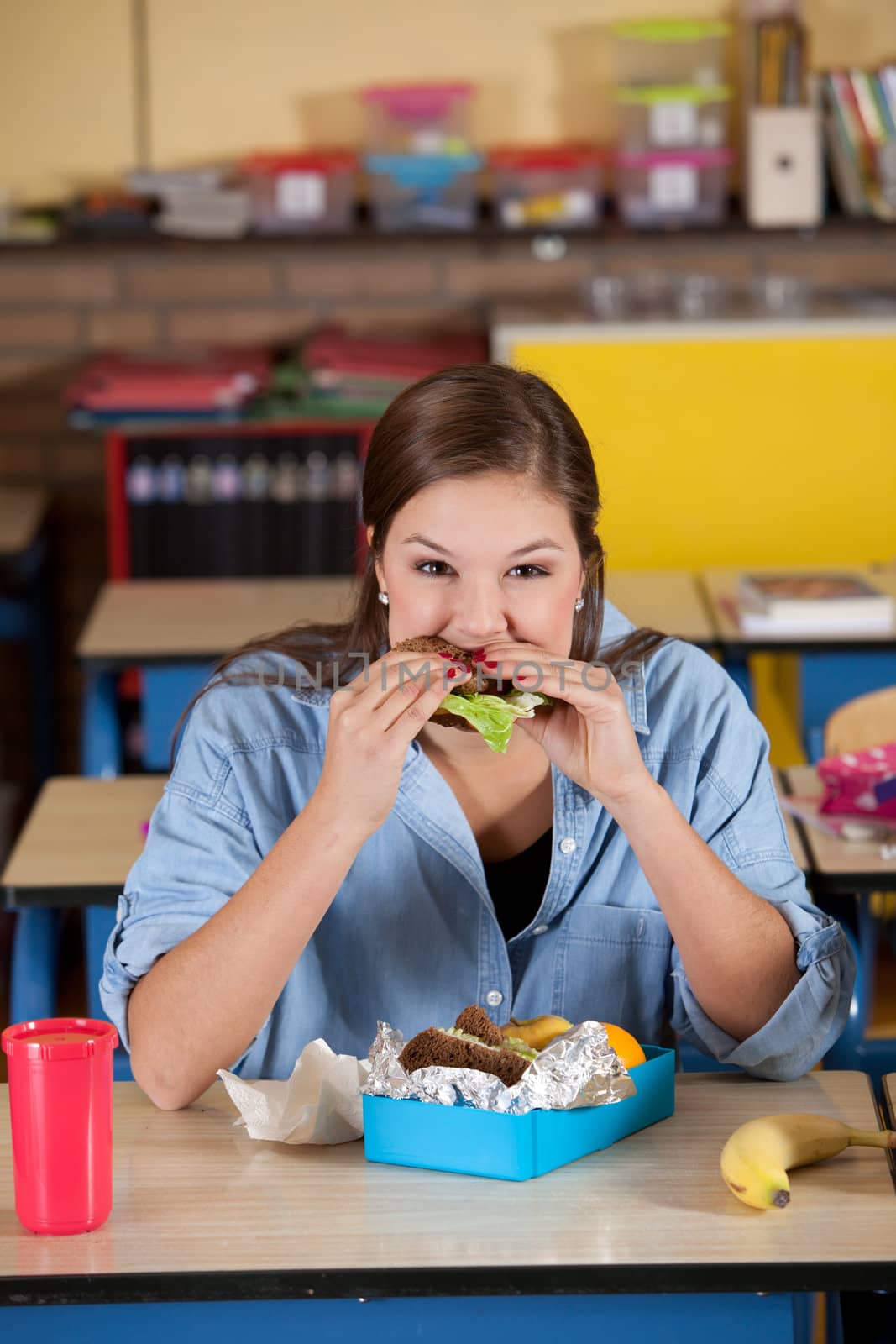 Young schoolgirl taking a bite of her healthy lunch