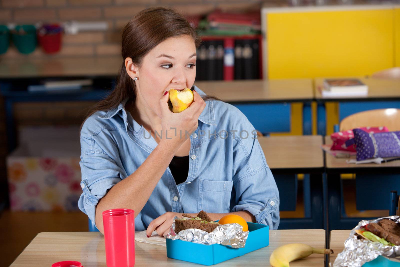Young student enjoying a tasty apple in the class room