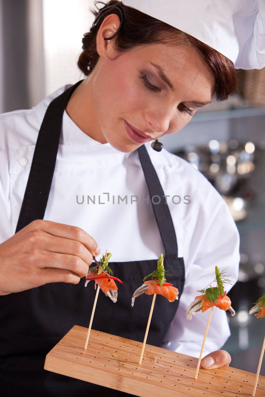 Female chef giving a cooking demonstration adding a drop of balsamico to her dish