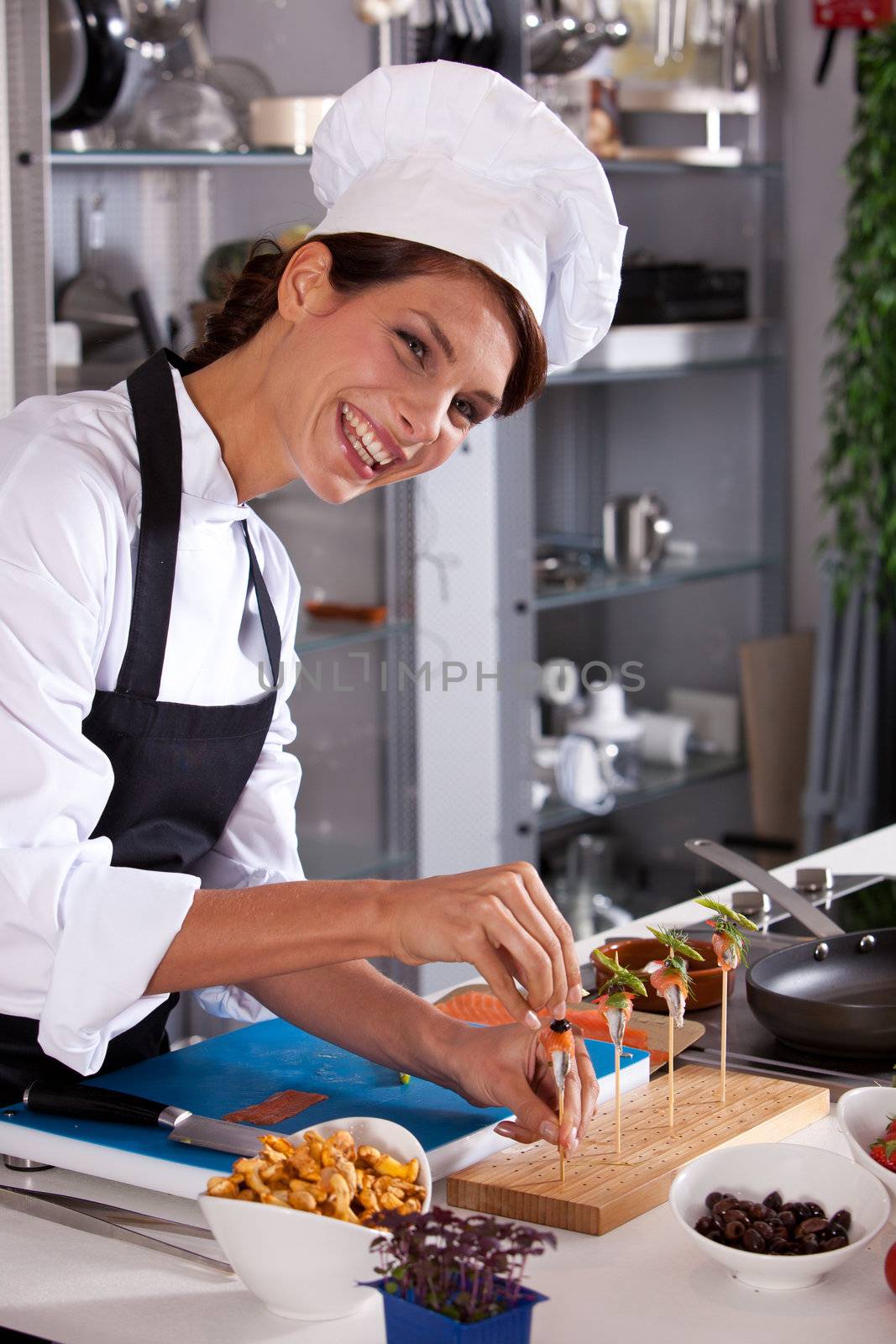 Laughing female chef preparing a small amuse on a stick
