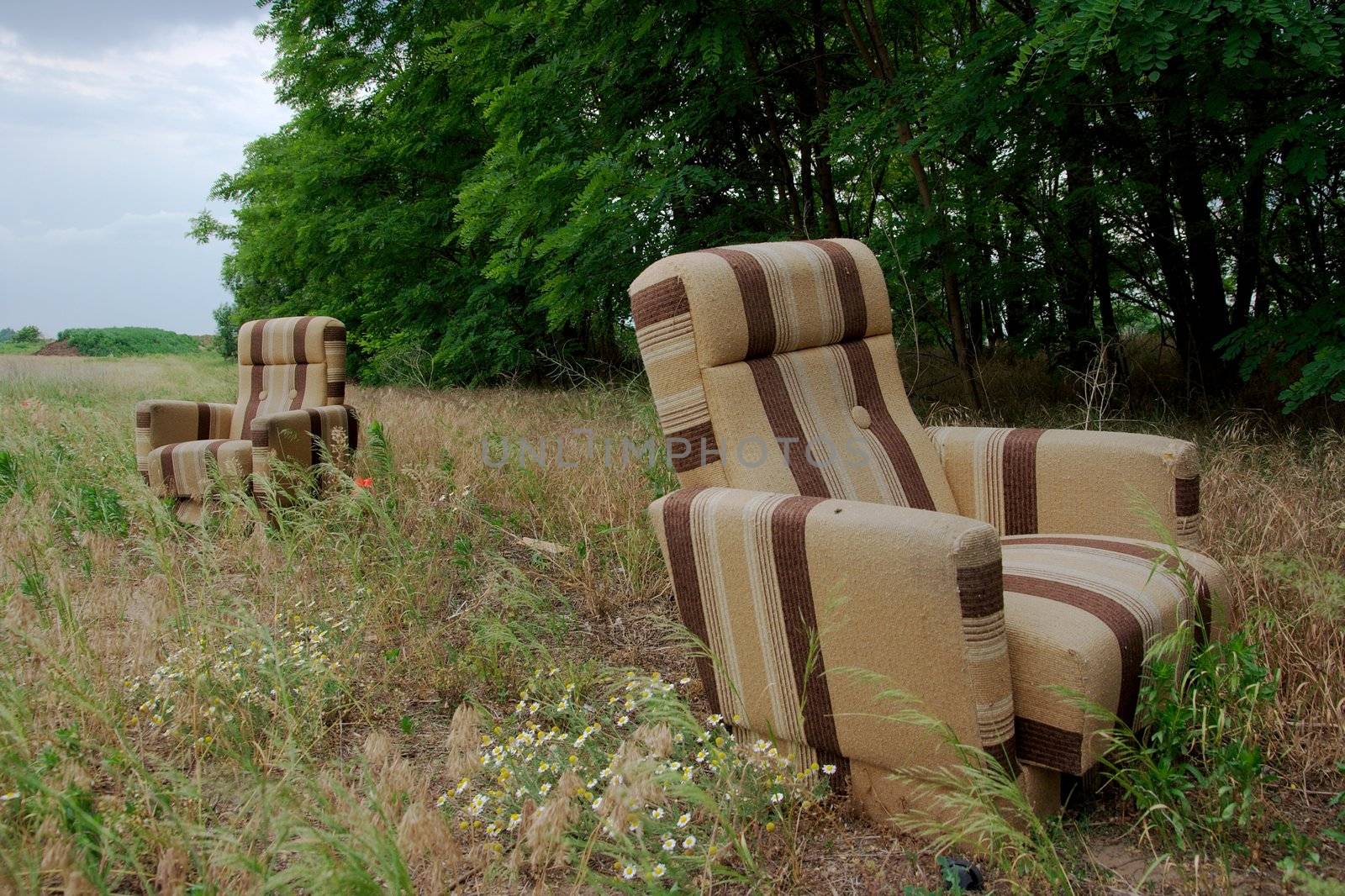 Two abandoned armchairs on a field