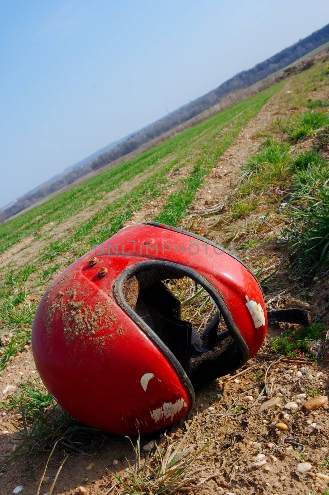 Red broken helmet on an agricultural field