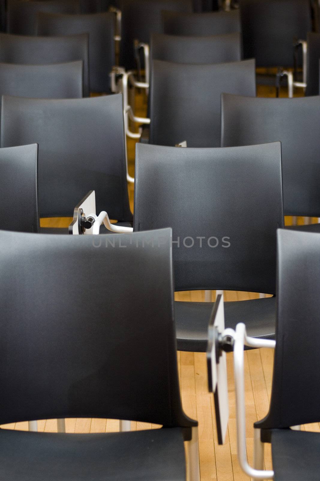 Empty black chairs in conference room. Shallow depth of field.