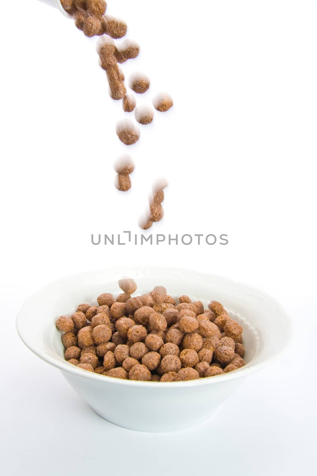 Chocolate balls falling in ceramic bowl-blur representing motion. Isolated on white.