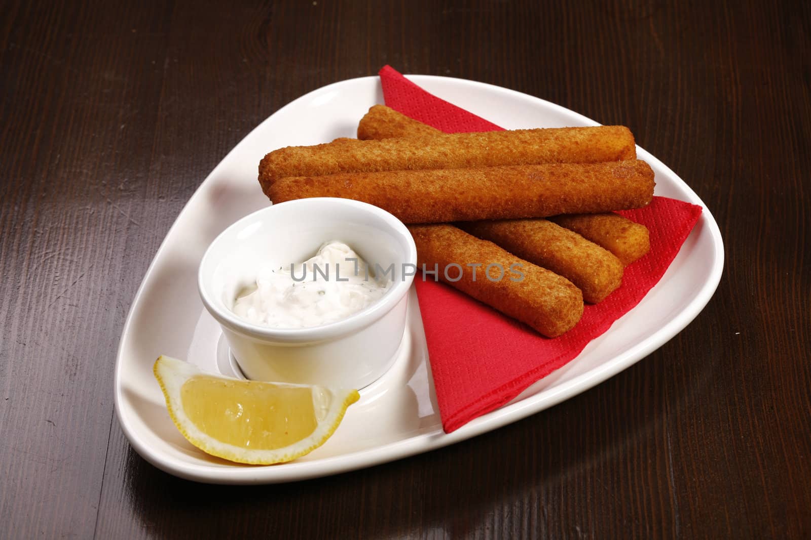 roasted cheese sticks on white plate on brown table with clipping path