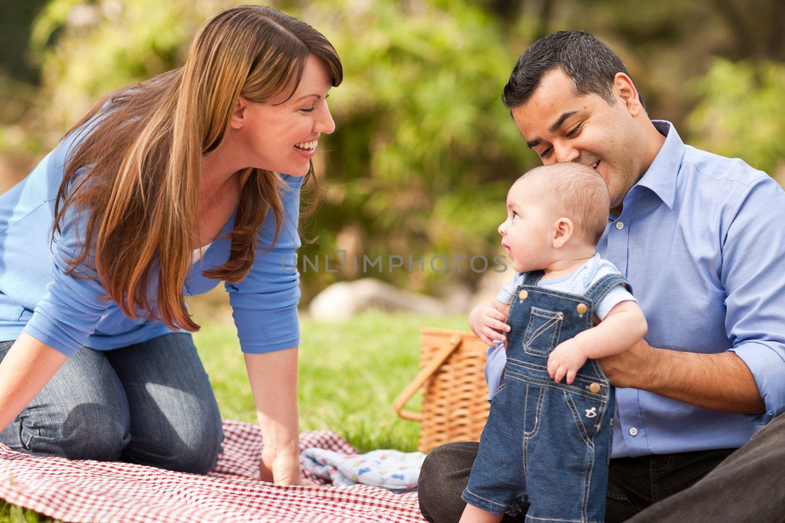 Happy Mixed Race Family Having a Picnic and Playing In The Park.