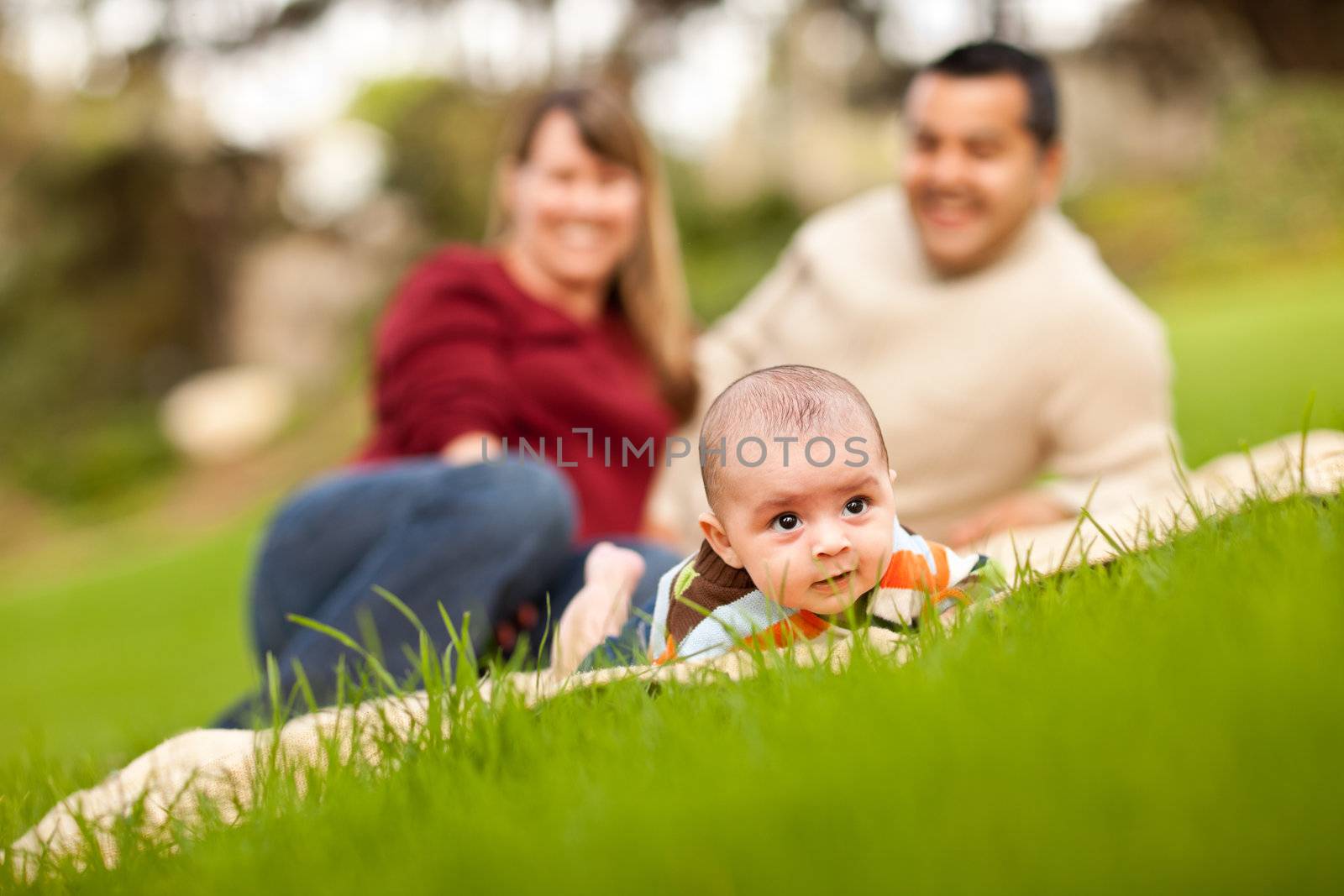 Happy Crawling Baby Boy and Mixed Race Parents Playing in the Park.