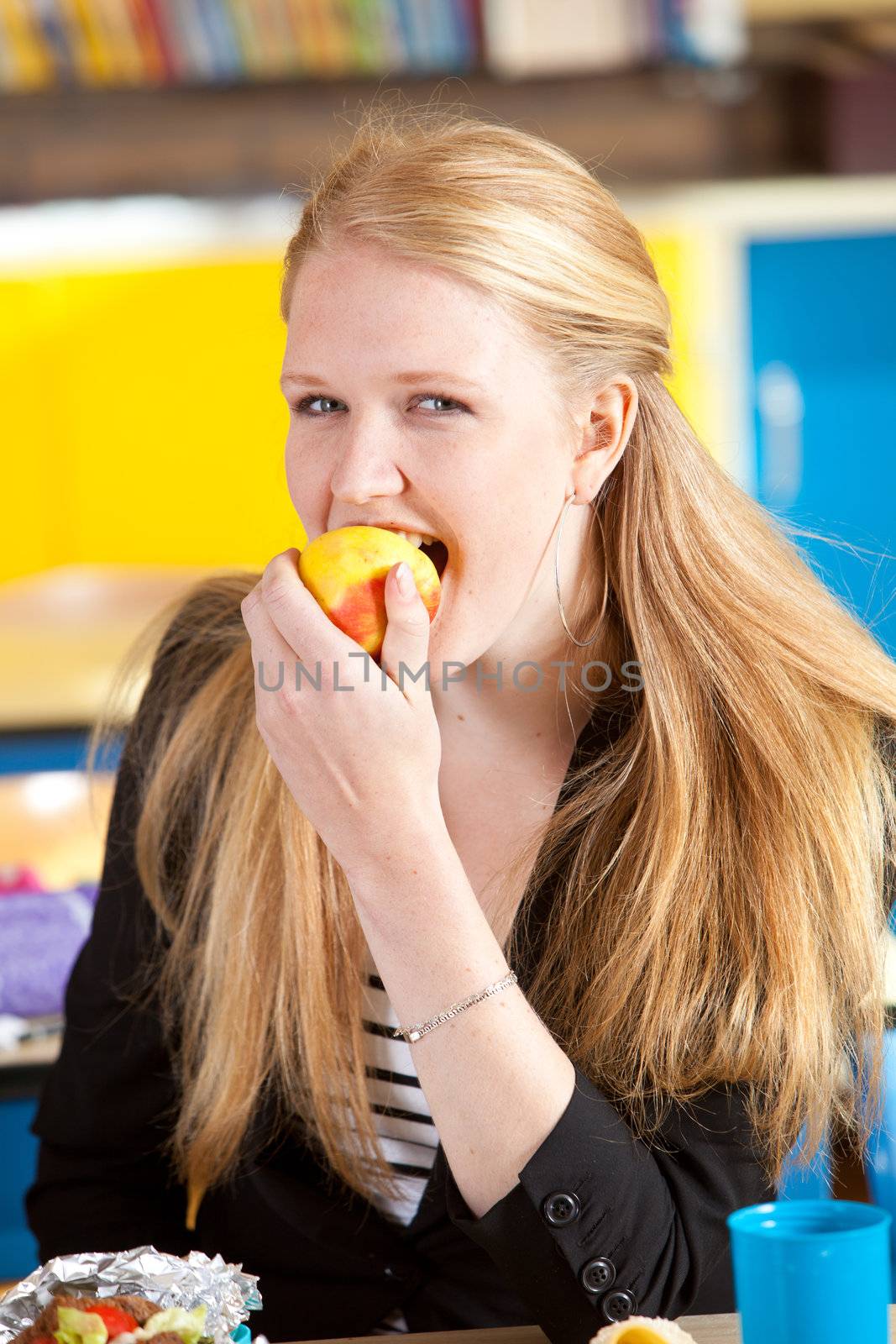 Blond schoolgirl eating an apple