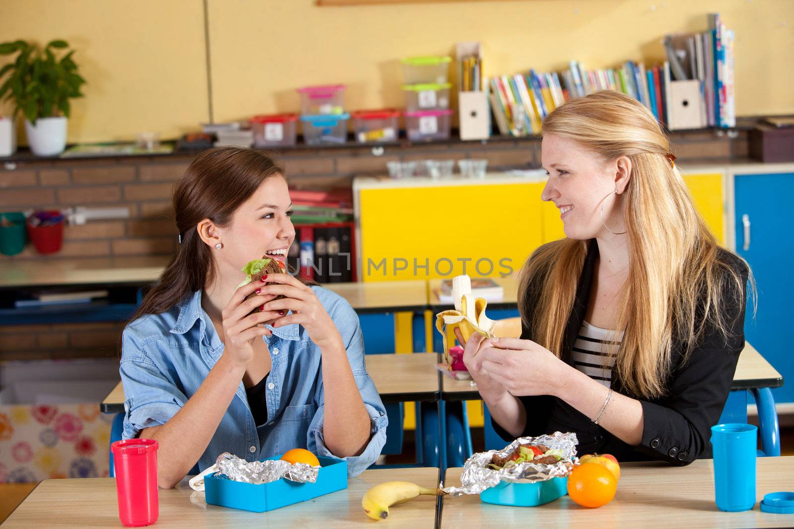 Two teenage girls having a healthy lunch in the classroom