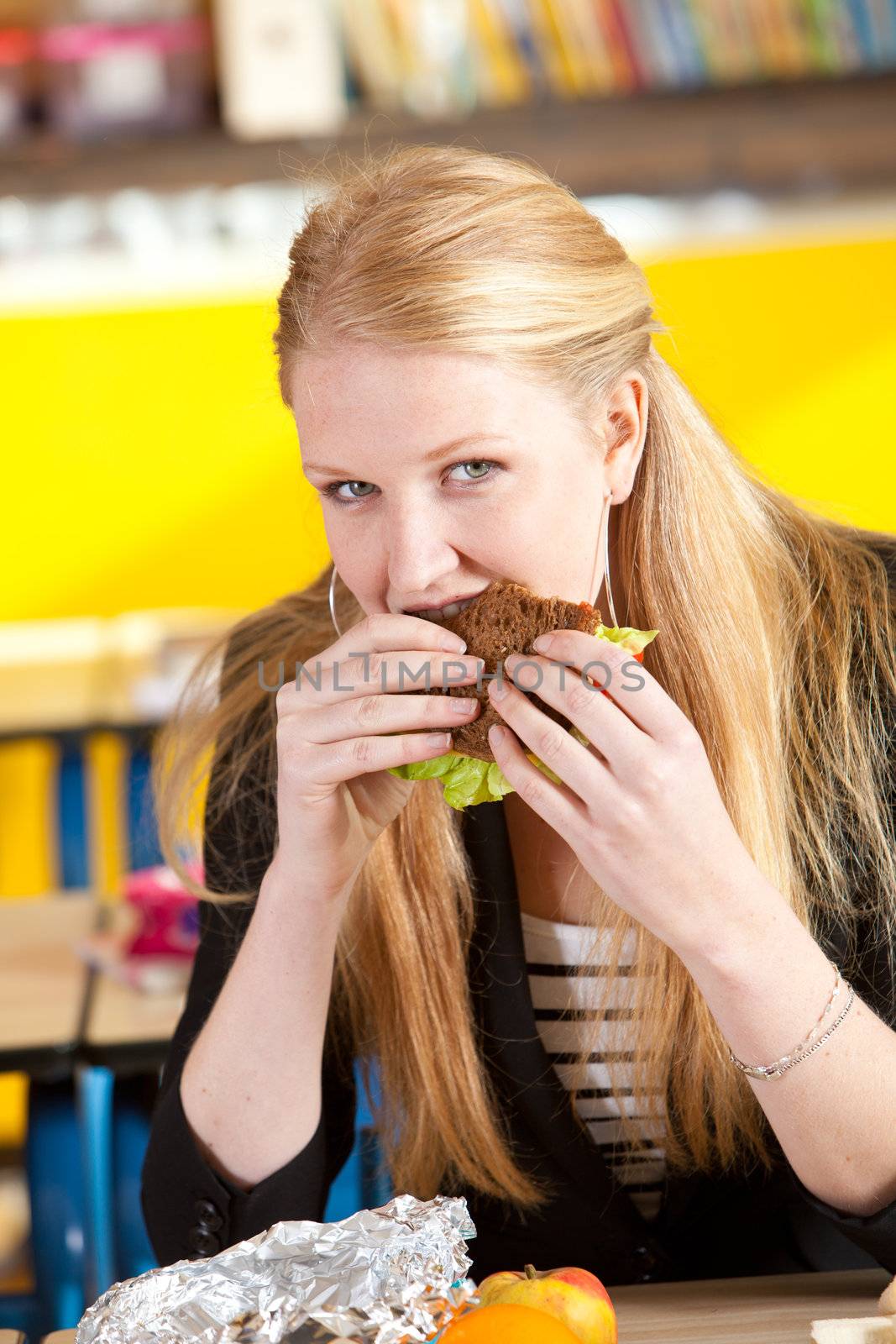 Pretty blond teenager taking a bite of her healthy sandwich