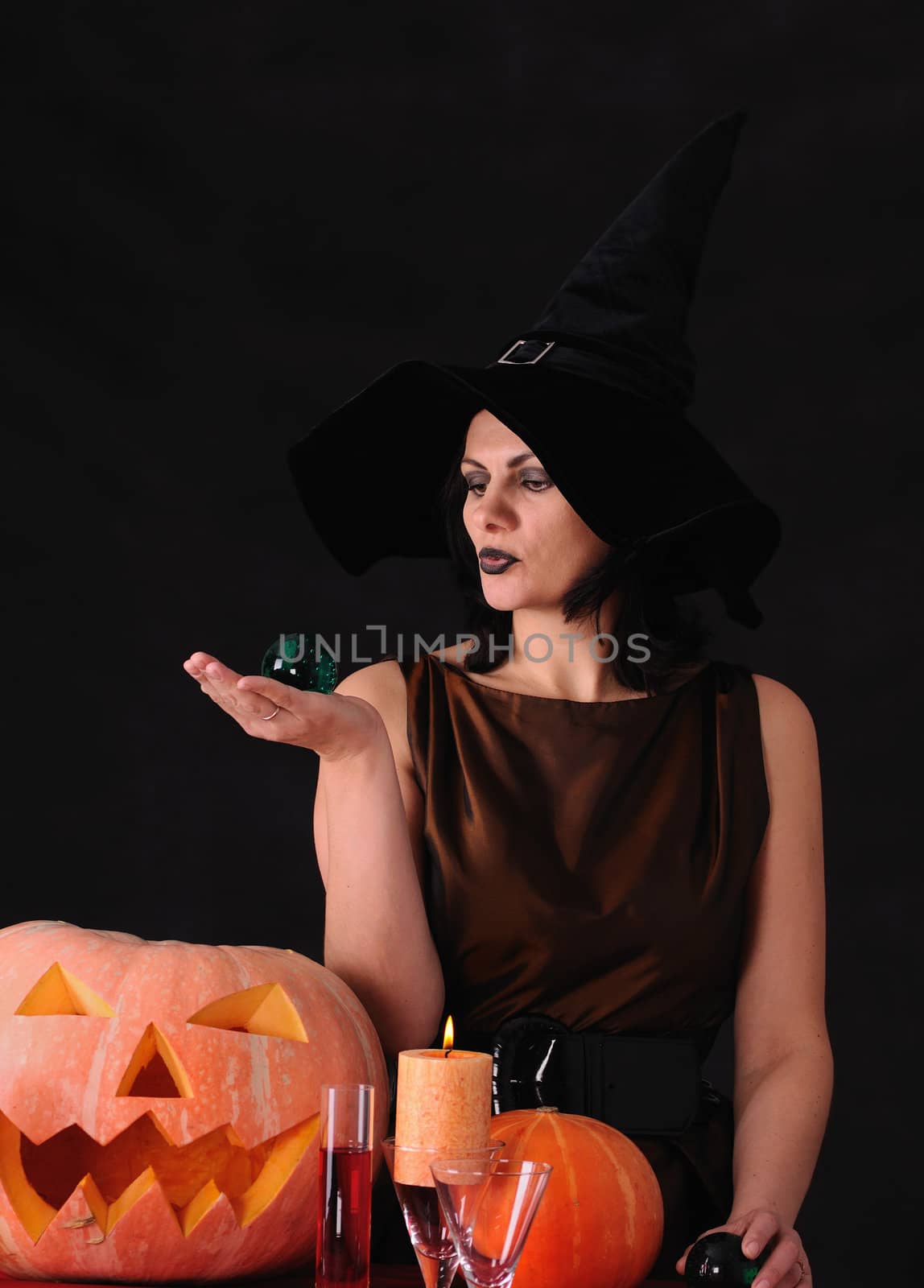 Young witch with a pumpkin on a black  background
