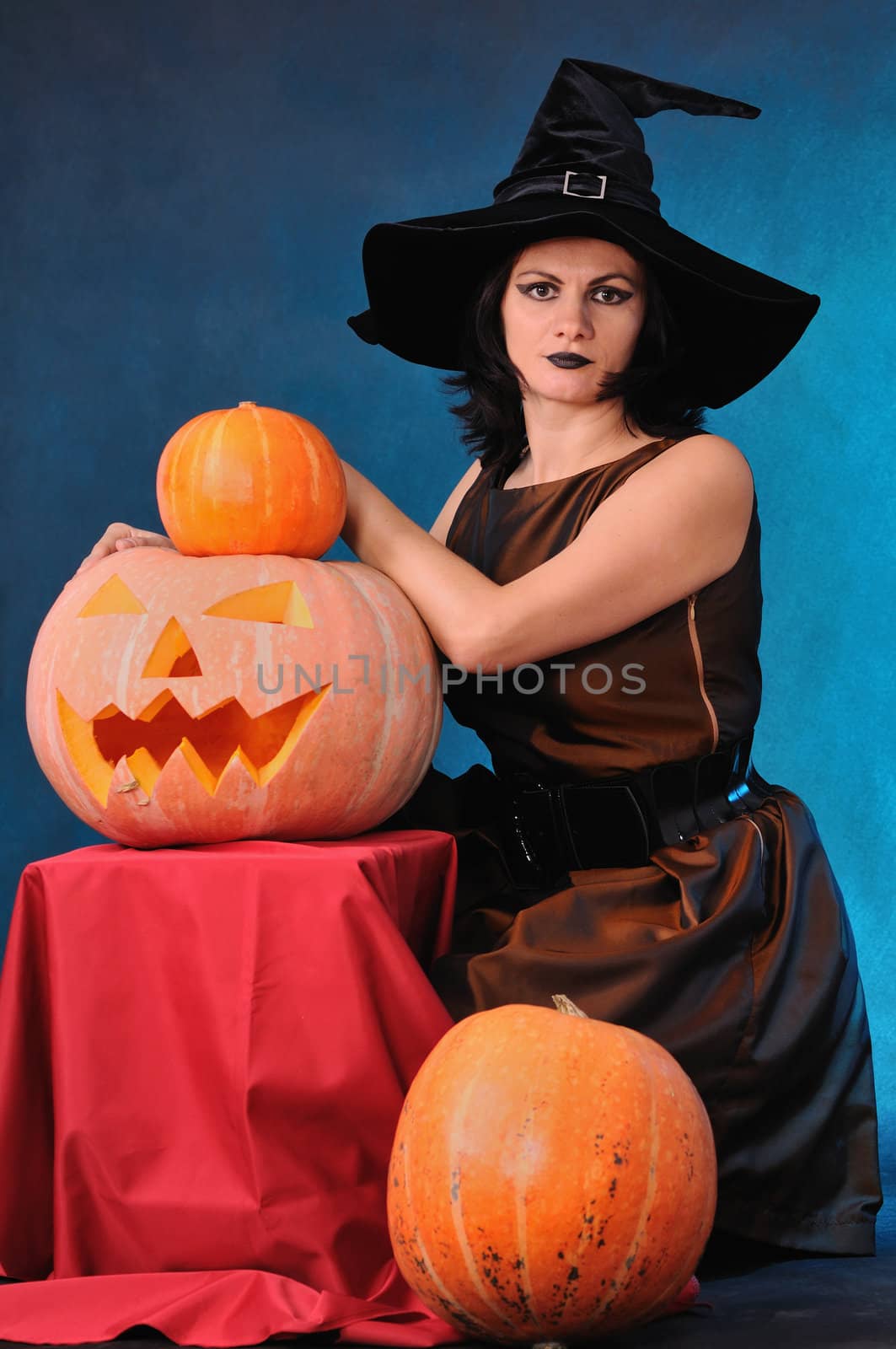 Young witch with a pumpkin on a blue  background