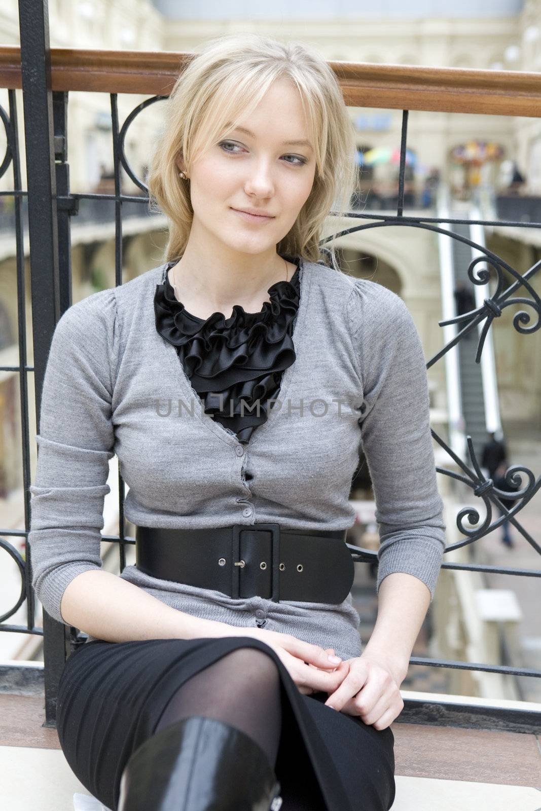 young attractive woman sitting at railing in state department store. Shopping. Moscow