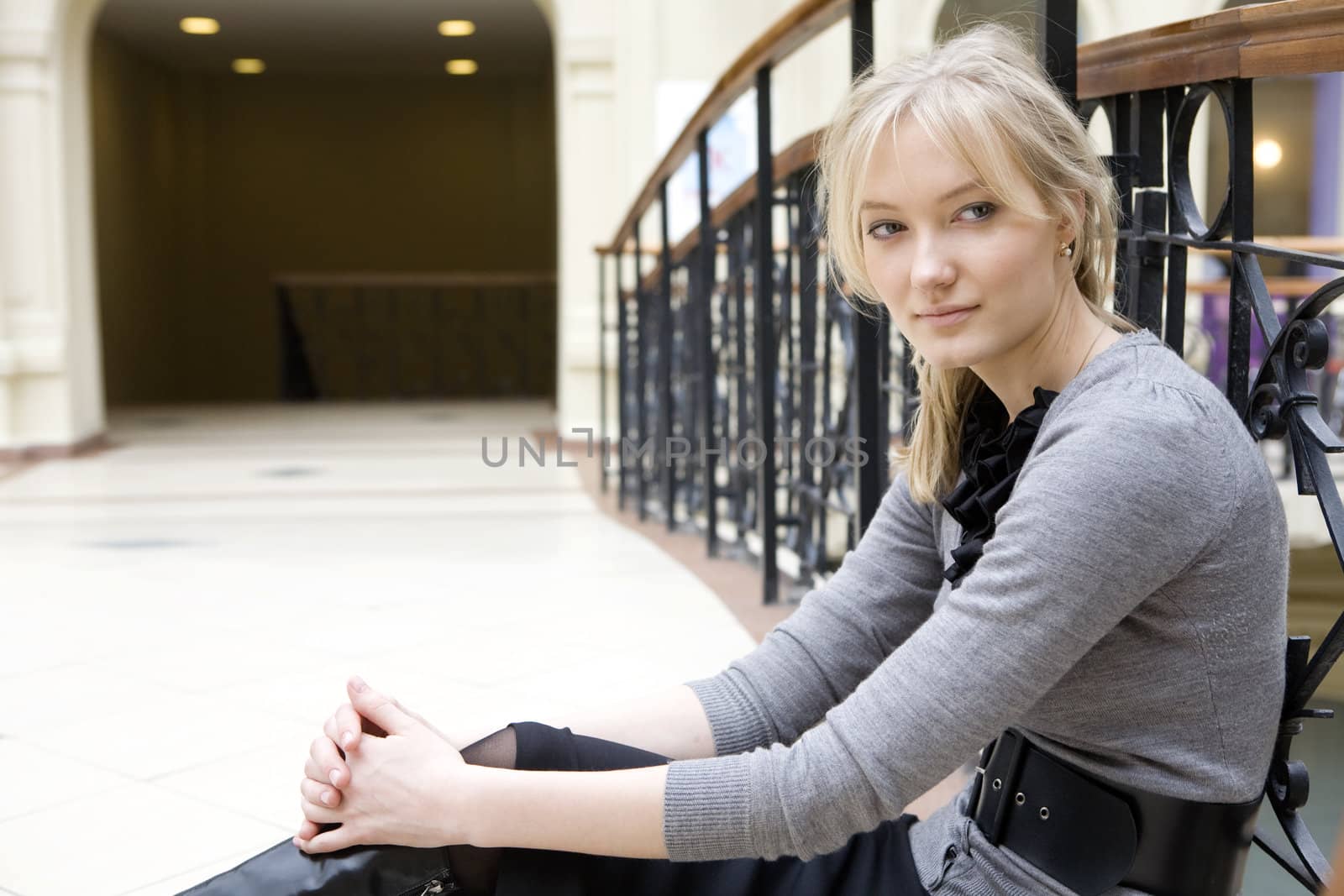young attractive blond woman sitting at railing in state department store. Tired form shopping Moscow