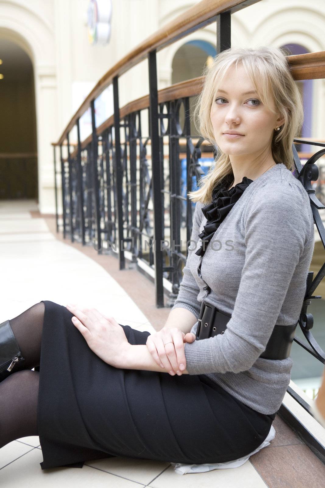 young attractive tired blond woman sitting at railing in state d by elenarostunova