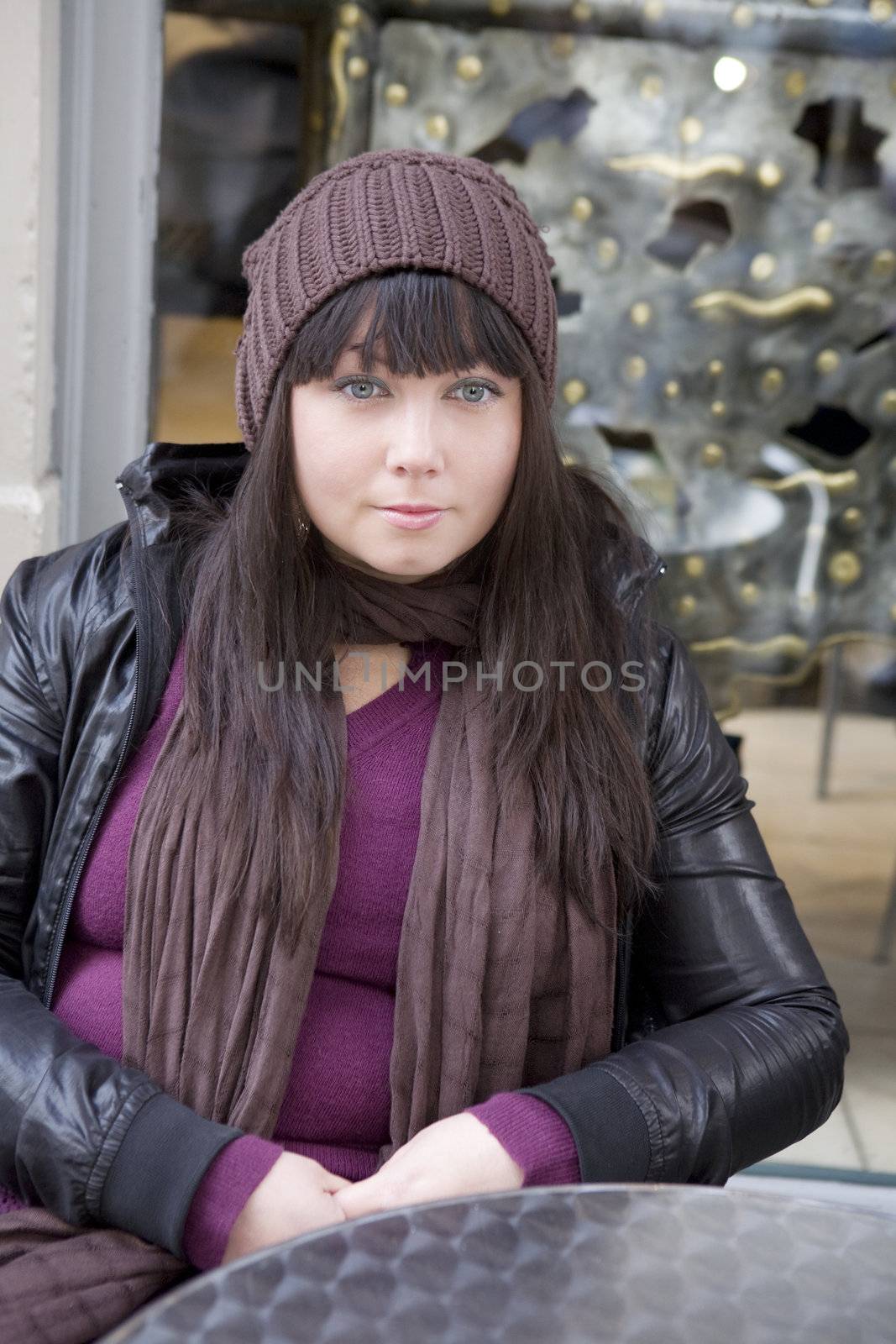 Attractive serious girl wearing cap is sitting in cafe outdoor by elenarostunova