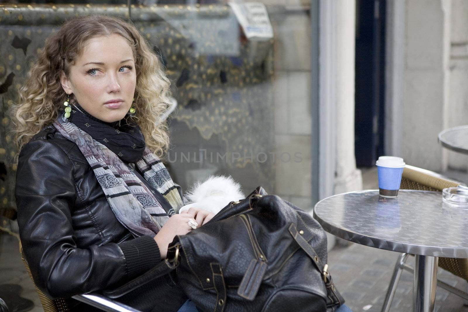 attractive blond curl  girl sitting in open-air cafe in London by elenarostunova