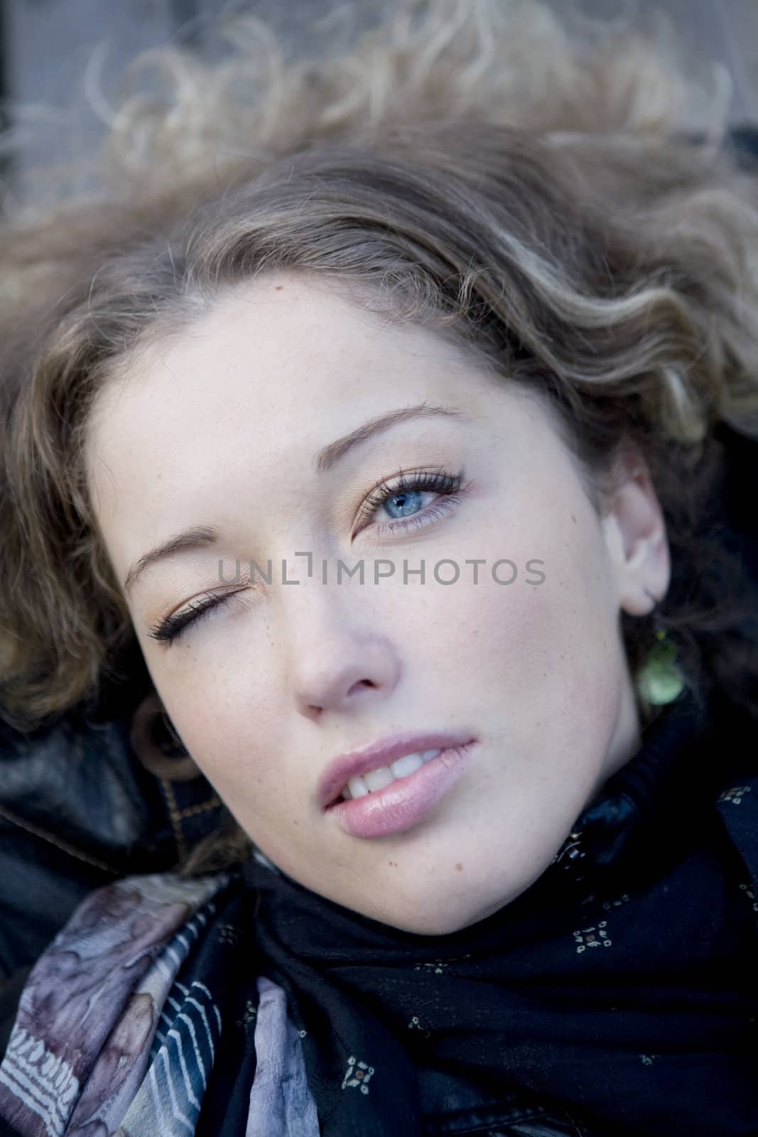 closeup portrait young curl blond winking  woman with blue eyes