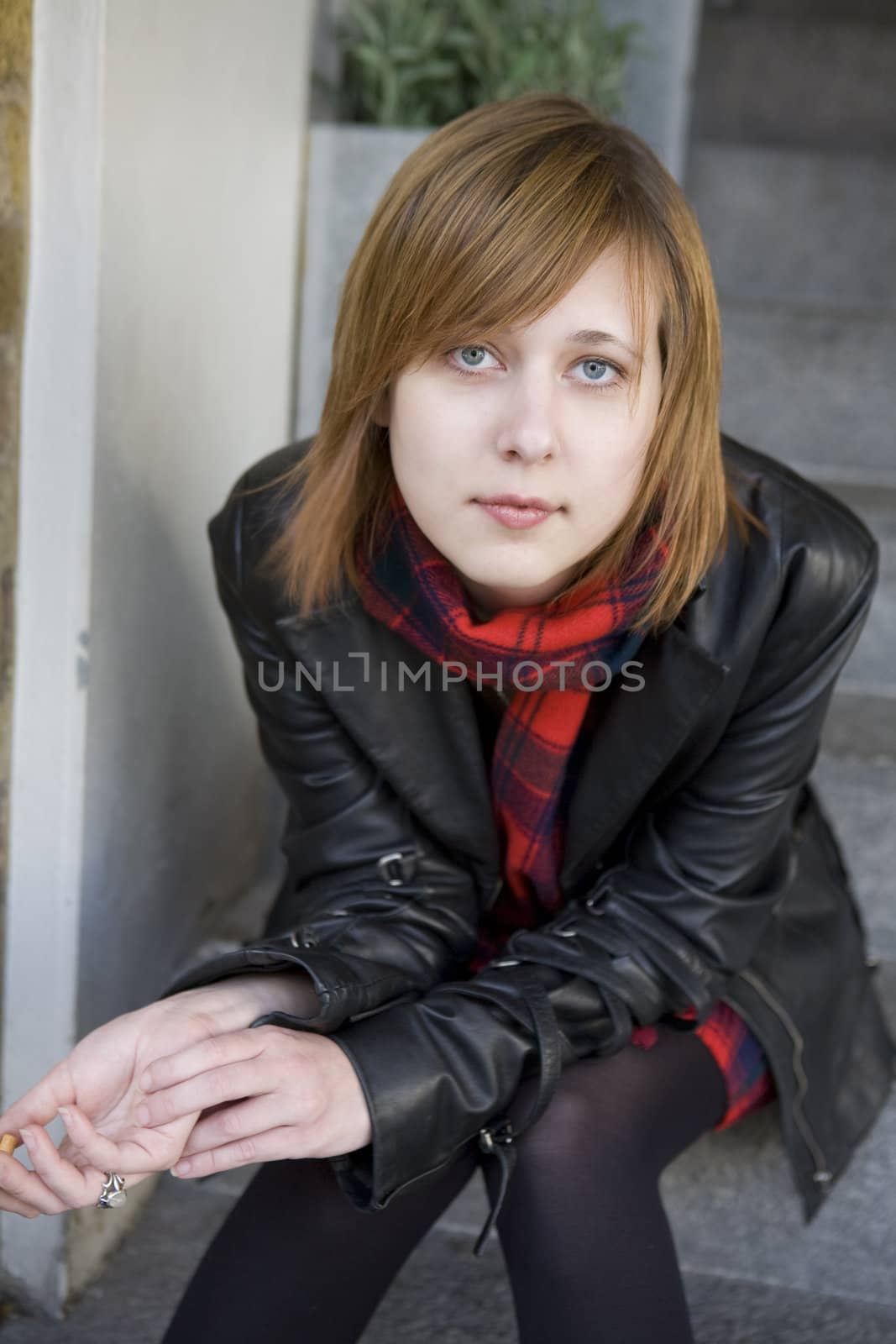 young attractive girl with red hair sitting on street, waiting