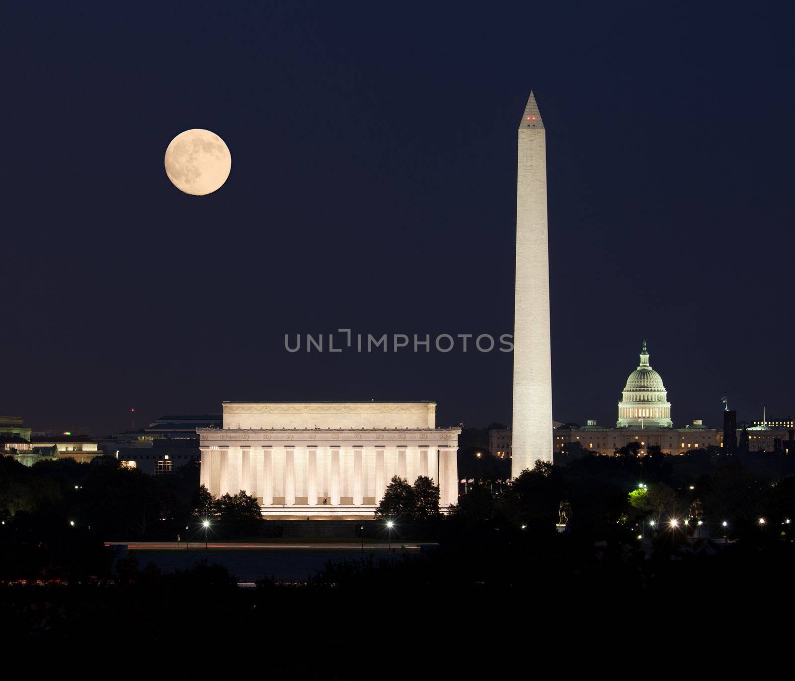 Full Harvest moon rising above the Lincoln Memorial with Washington Monument and Capitol building aligned