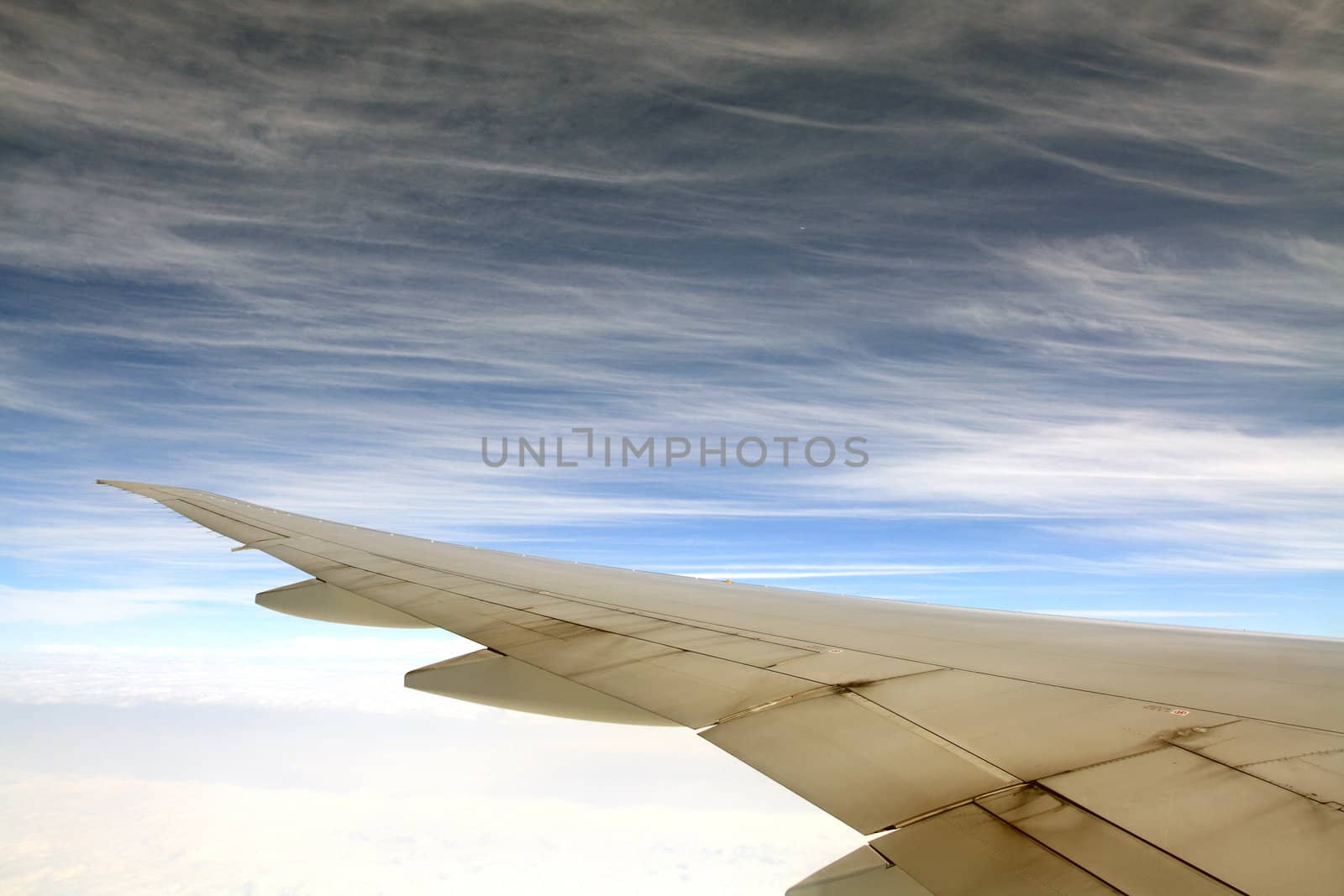 wings of an airplane in the blue sky by yucelunal