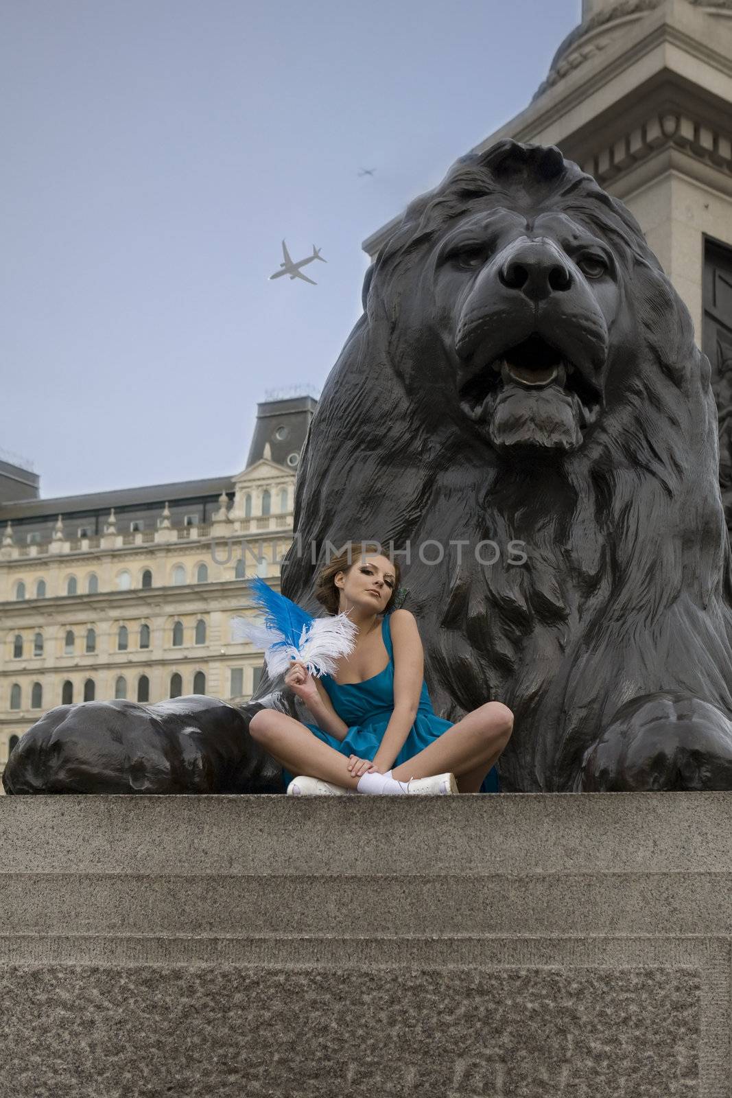 young adult girl sitting at monument of lion. Trafalgar Square. London