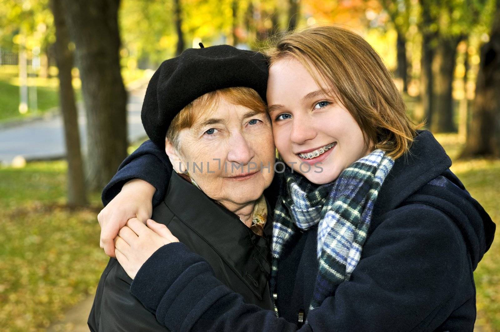 Teen granddaughter hugging grandmother in autumn park