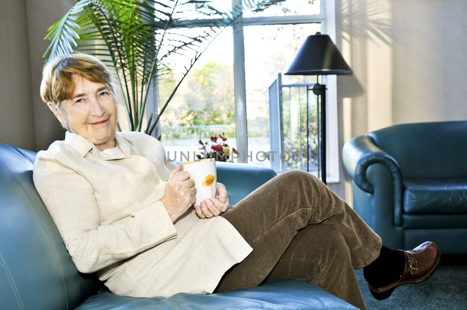 Senior woman sitting and smiling happily with cup of tea