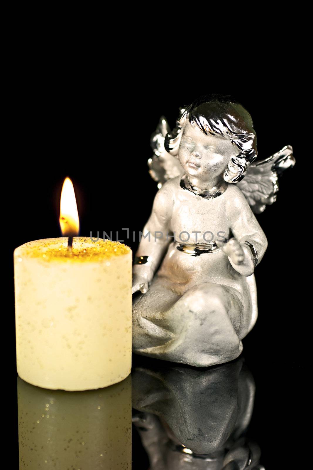 Christmas Angel staring at a burning candle. 