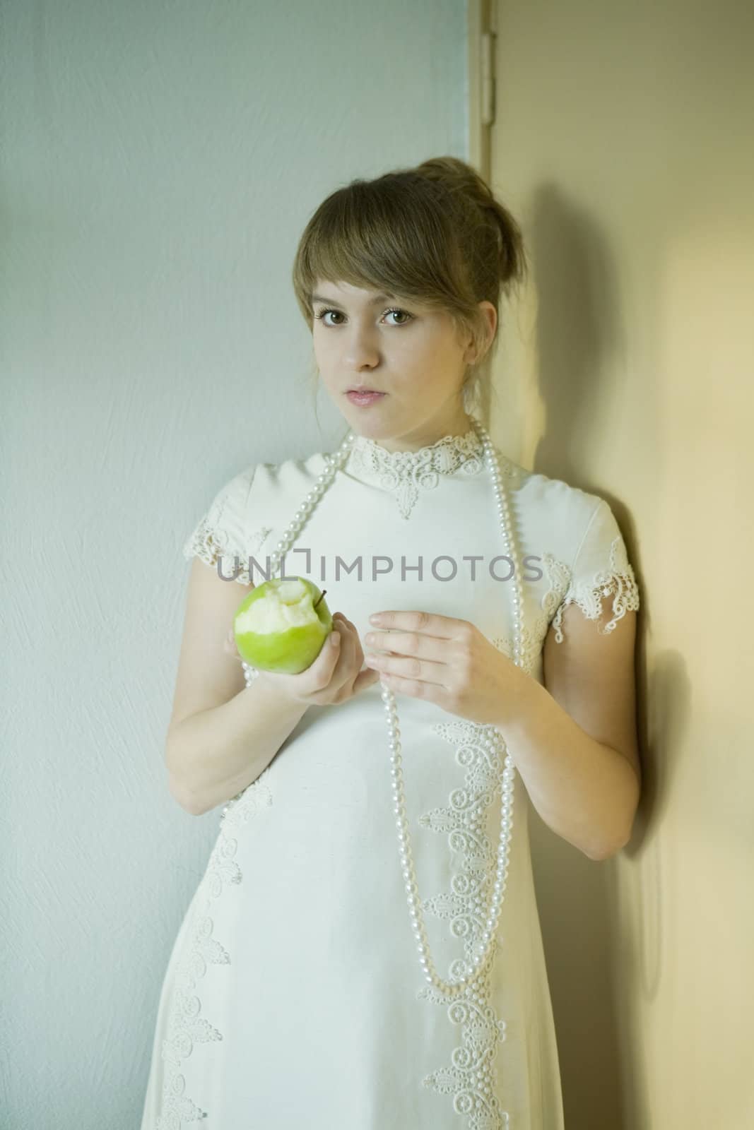 portrait of young attractive woman with apple standing at the wall