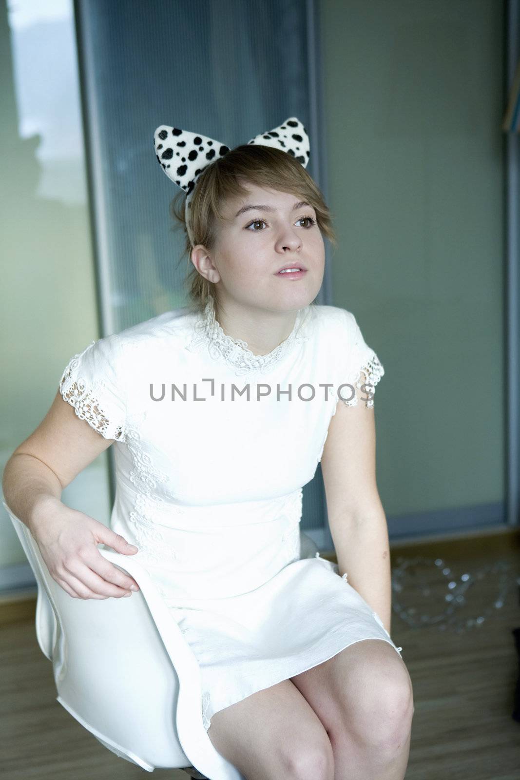 portrait of young cute thoughtful girl wearing white dress with dog`s ears