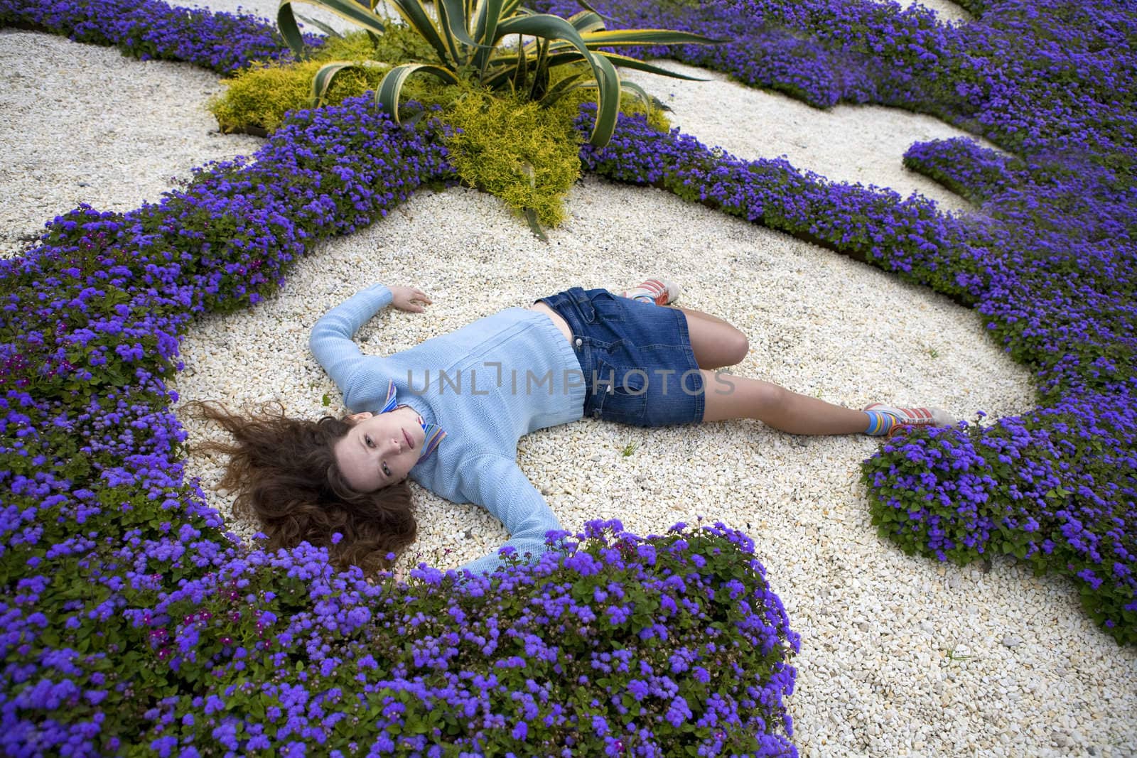 Attractive young woman lying between blue flower by elenarostunova