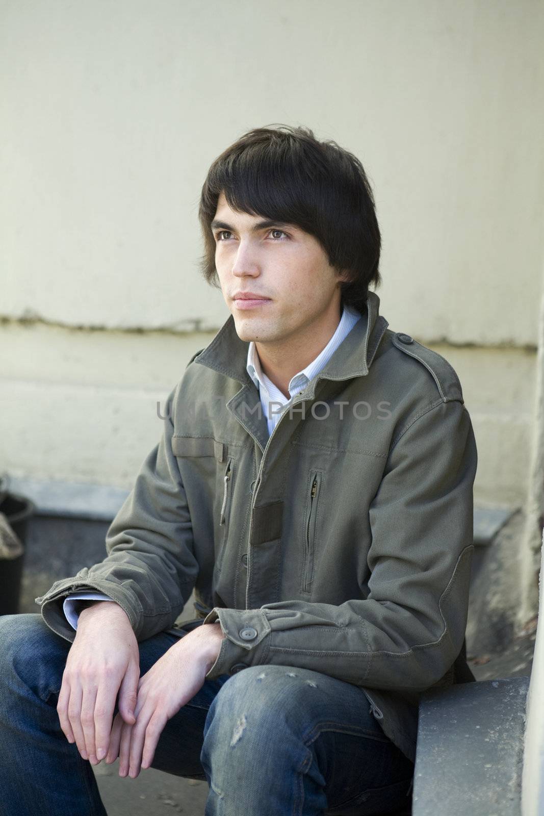 serious handsome man sitting on on the doorstep.