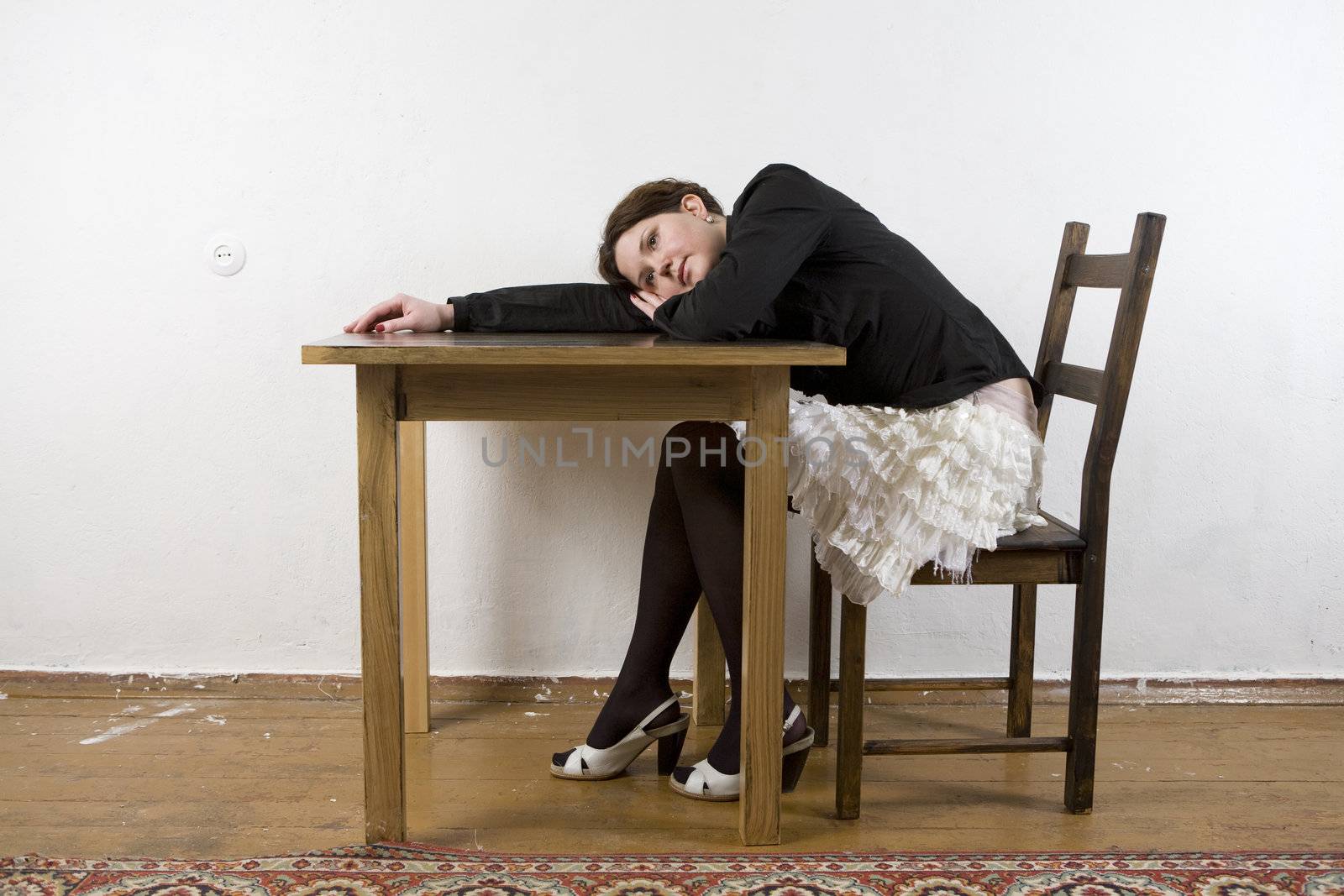 Young pensive attractive woman sitting on table put head on table. Woman`s trouble