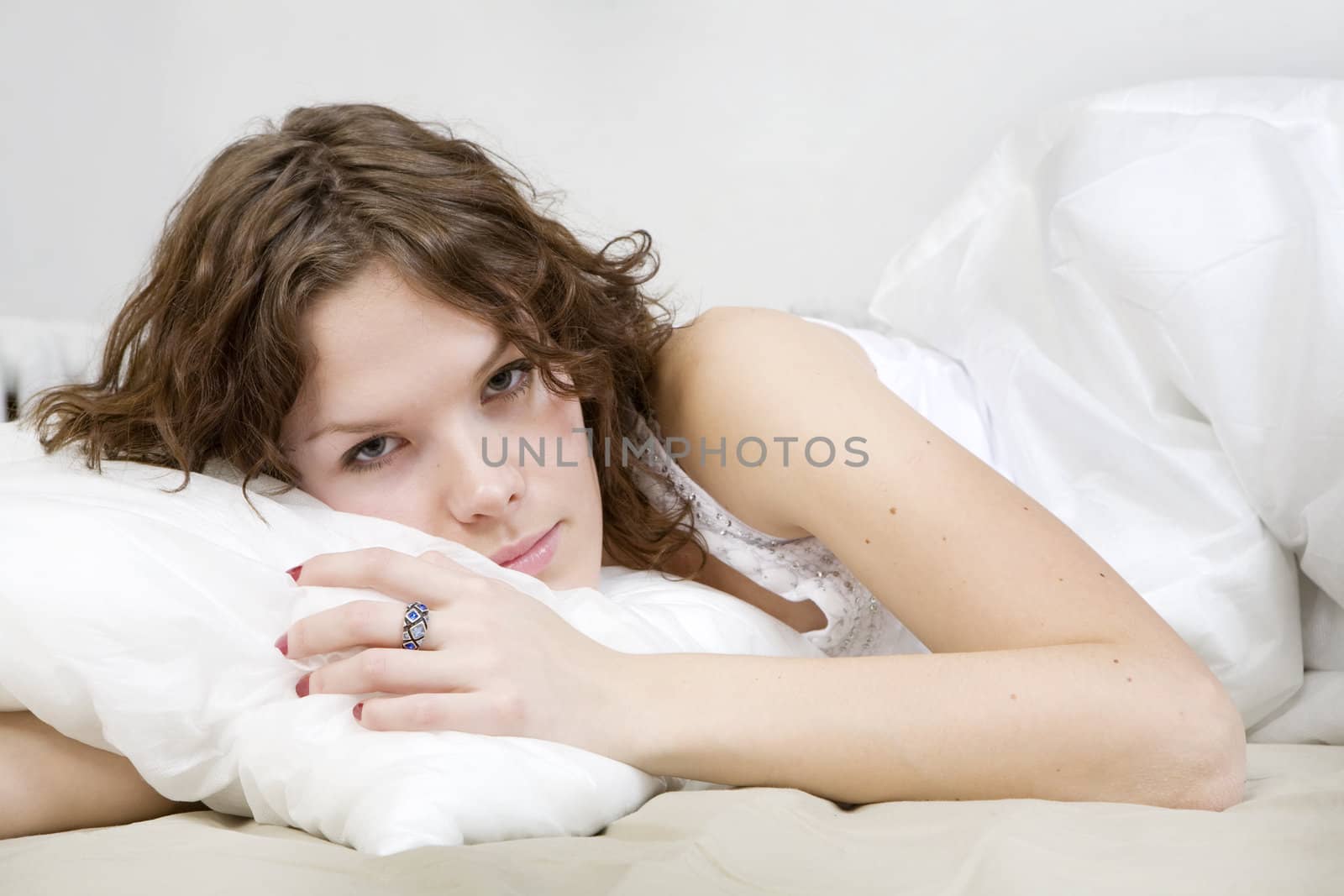 attractive thoughtful brunette curl woman with a pillow on the bed