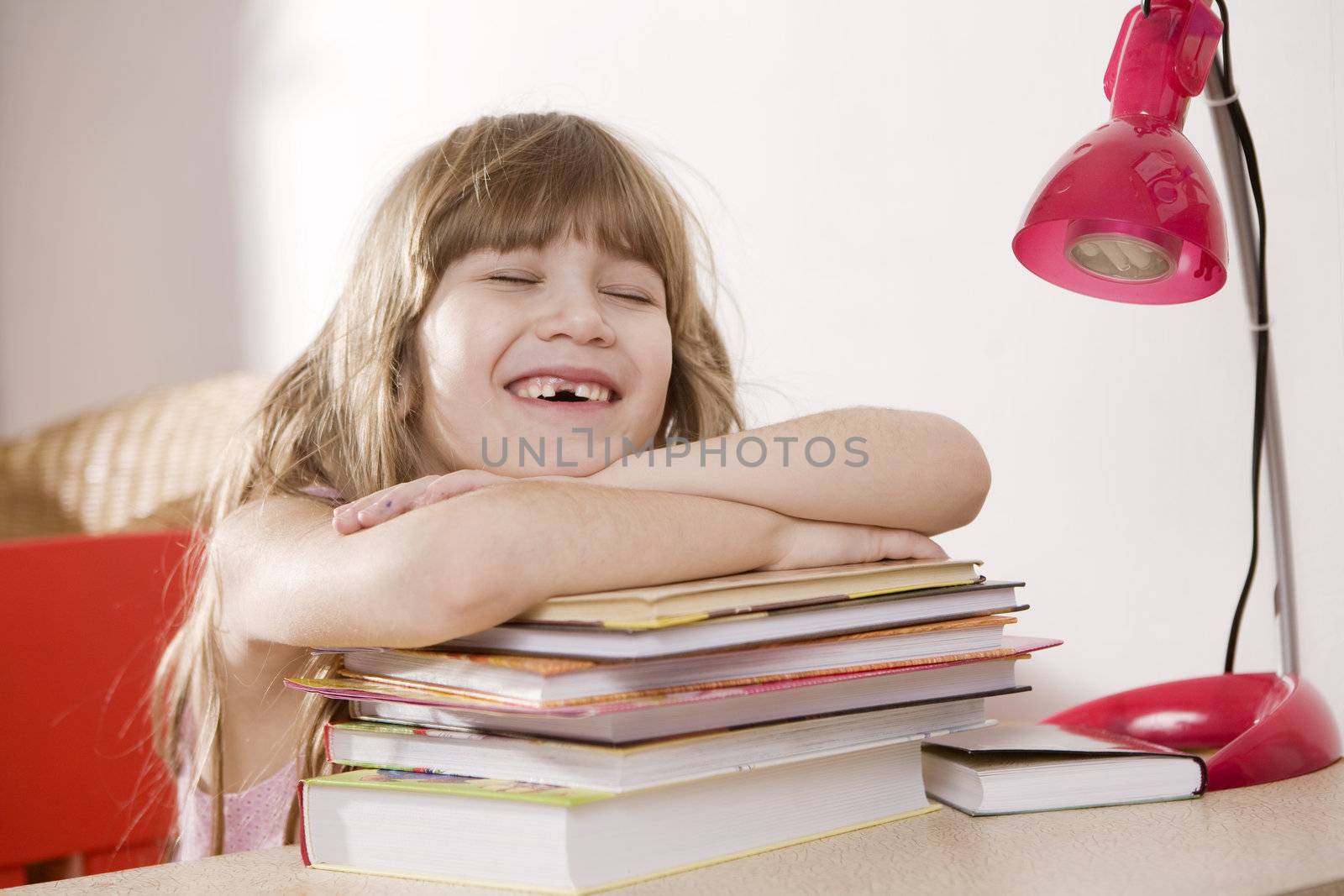 Little cute laughing  girl put head on books