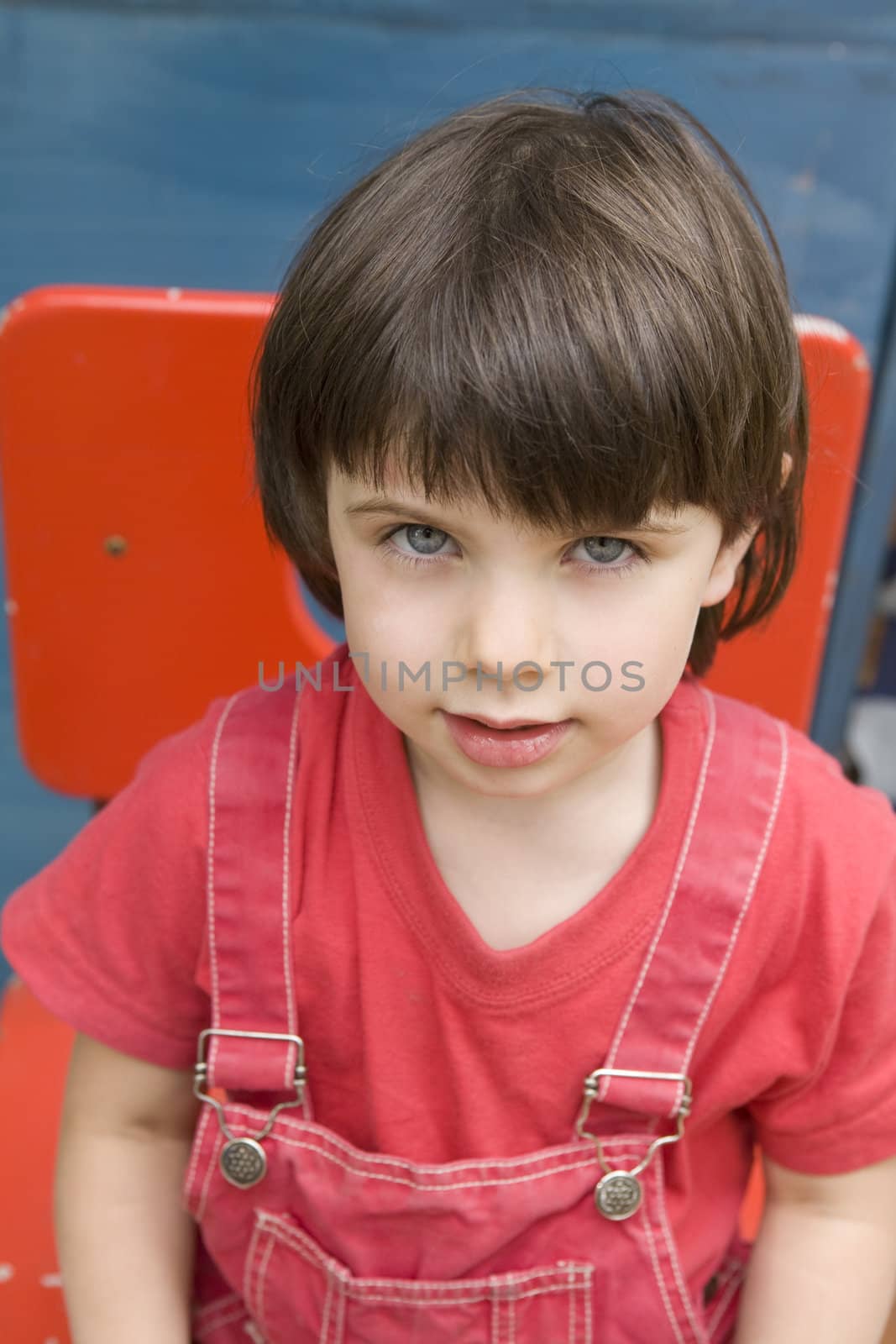 young serious  girl with blue eyes  in red sitting on red chair