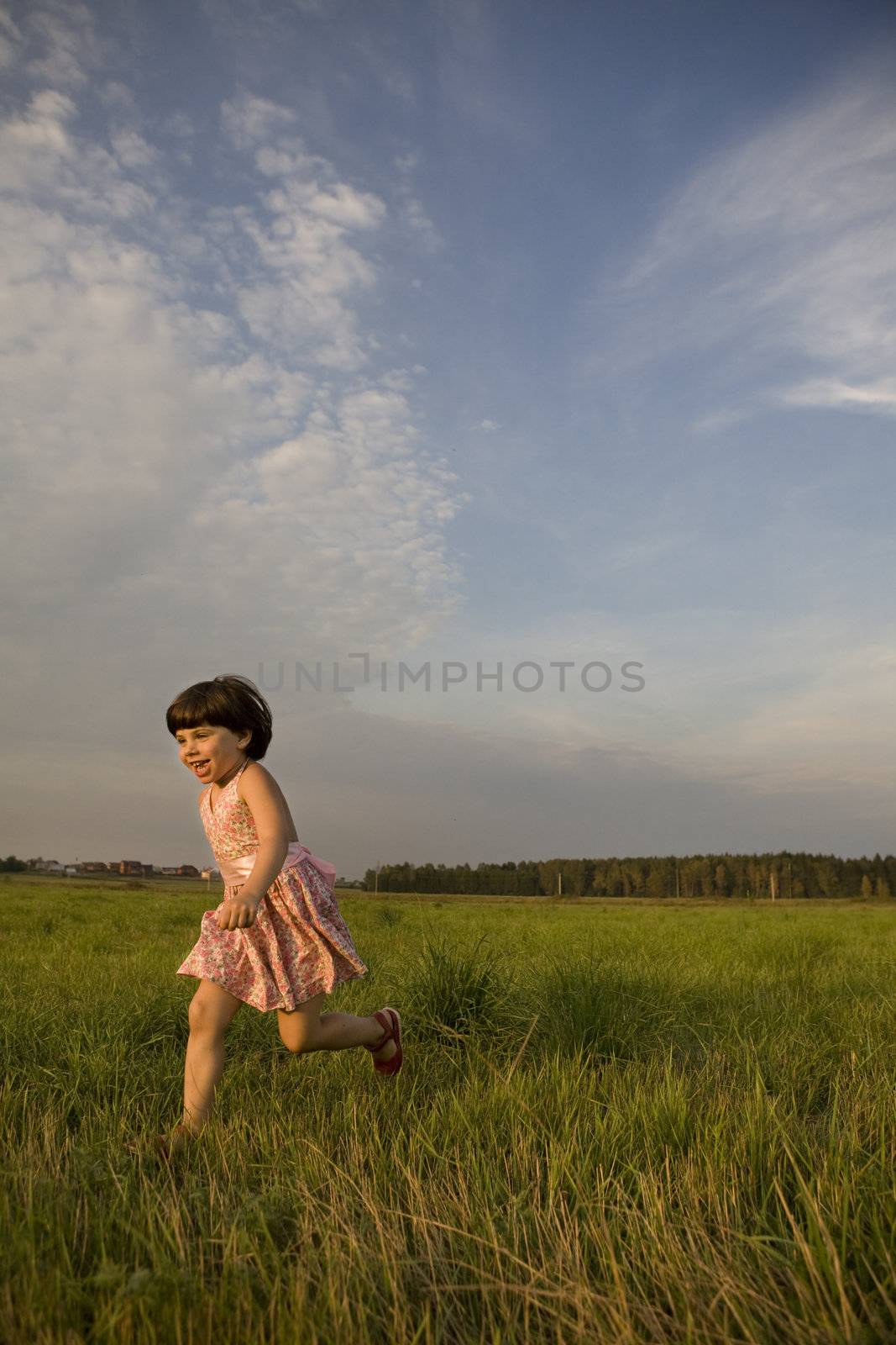 little cute girl running on meadow in sunset time. Summer time