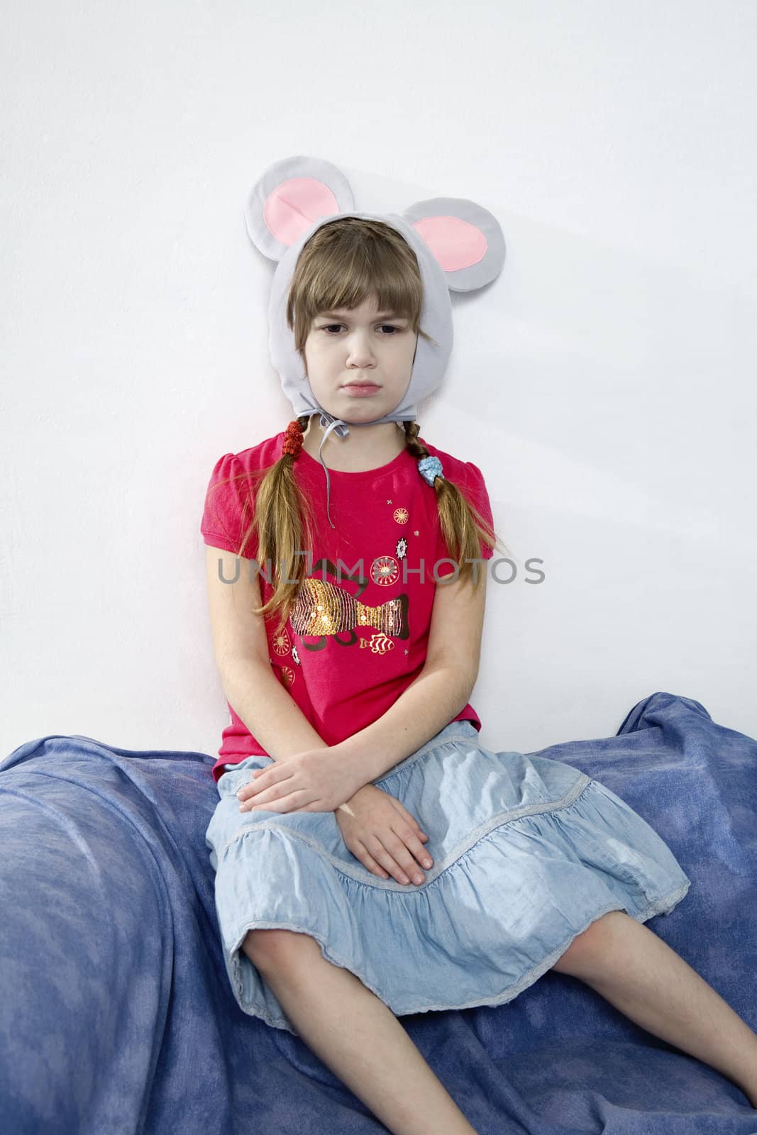 young cute upset girl wearing mouses`s ears sitting on the sofa