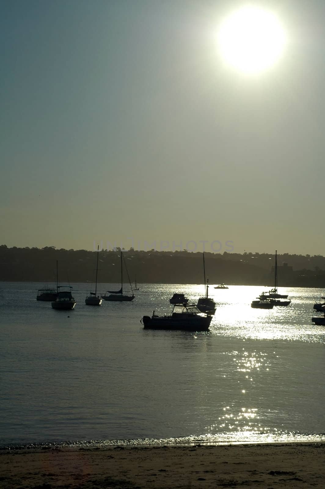 several anchoring boats, high contrast scene, white sun