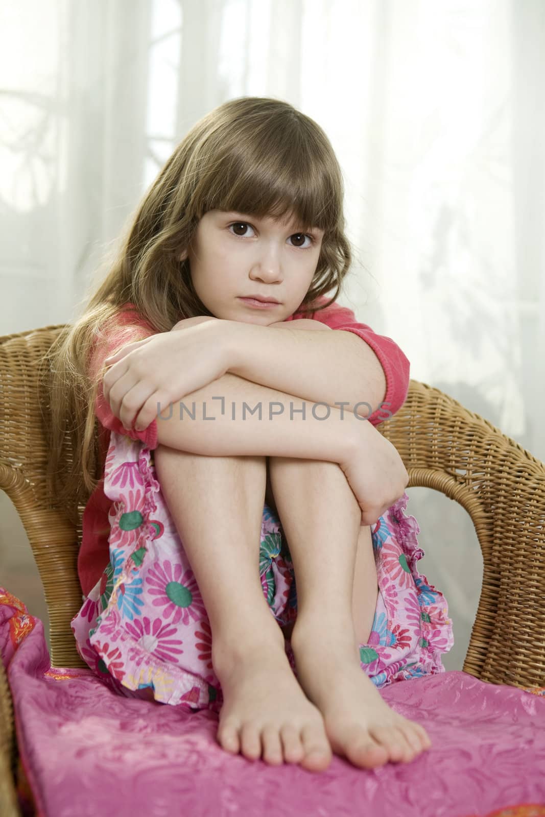 Little cute dreaming girl sitting on chair at window by elenarostunova