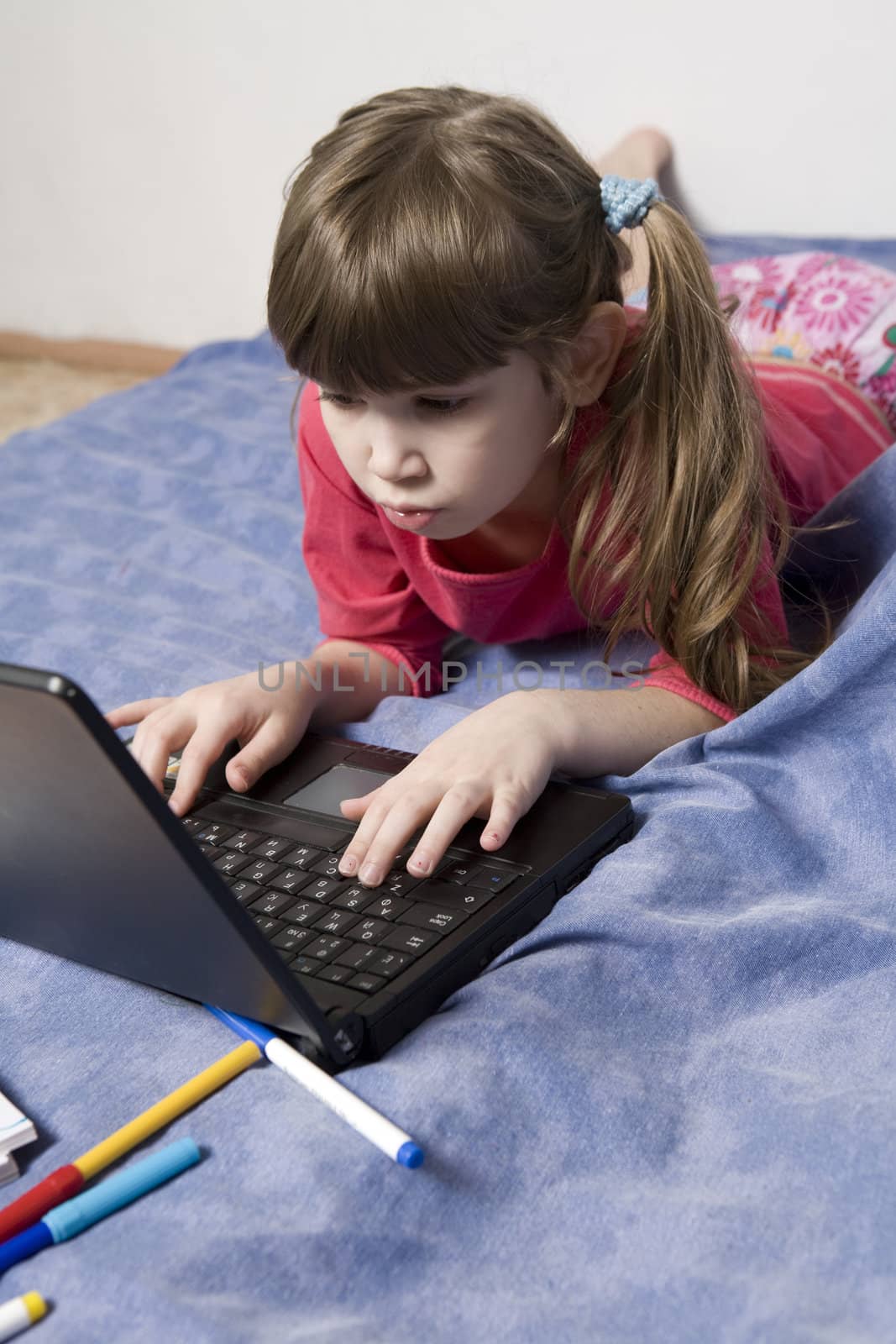 Cute little girl playing with computer by elenarostunova