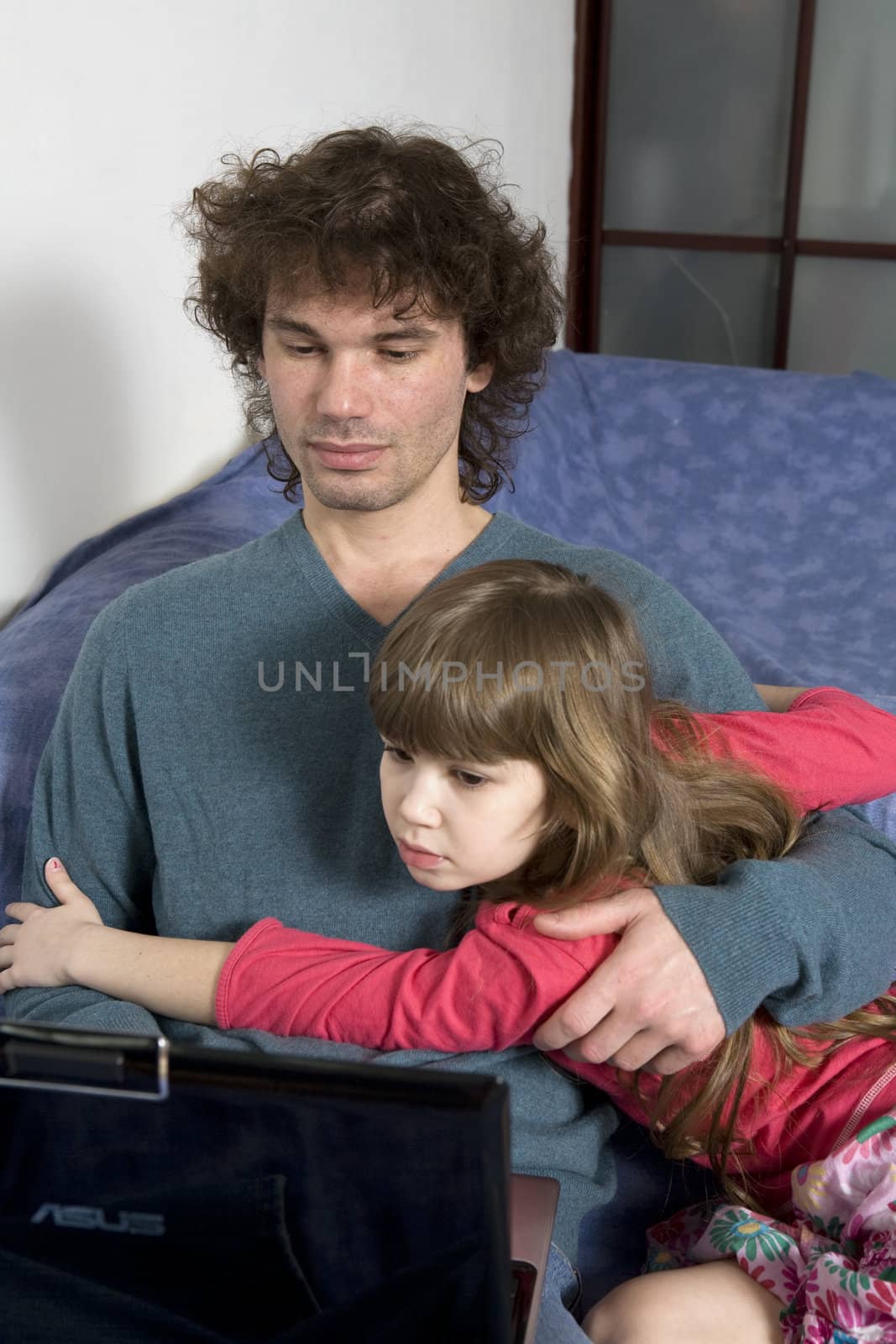 Father and daughter playing game sitting on the sofa using a lap by elenarostunova