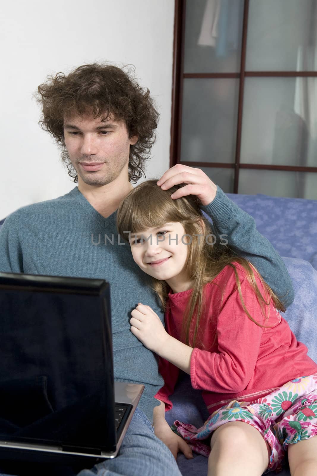 Father and daughter playing game sitting on the sofa using a lap by elenarostunova