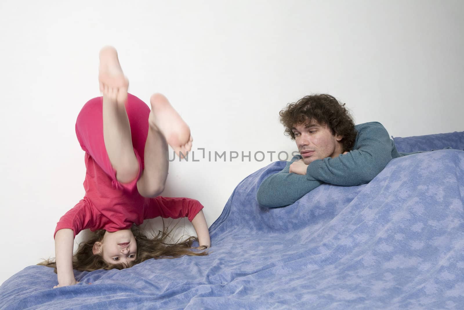 young smiling cute girl standing at head. Upside-down. Father watching it